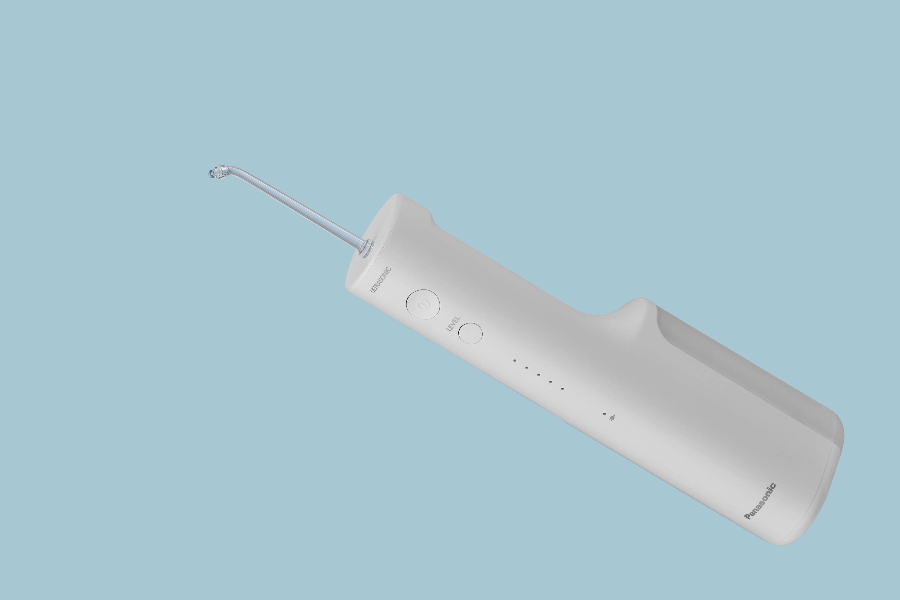 Bílá přenosná ústní sprcha před modrým pozadím. Design je štíhlý a moderní, s několika ovládacími tlačítky na straně.