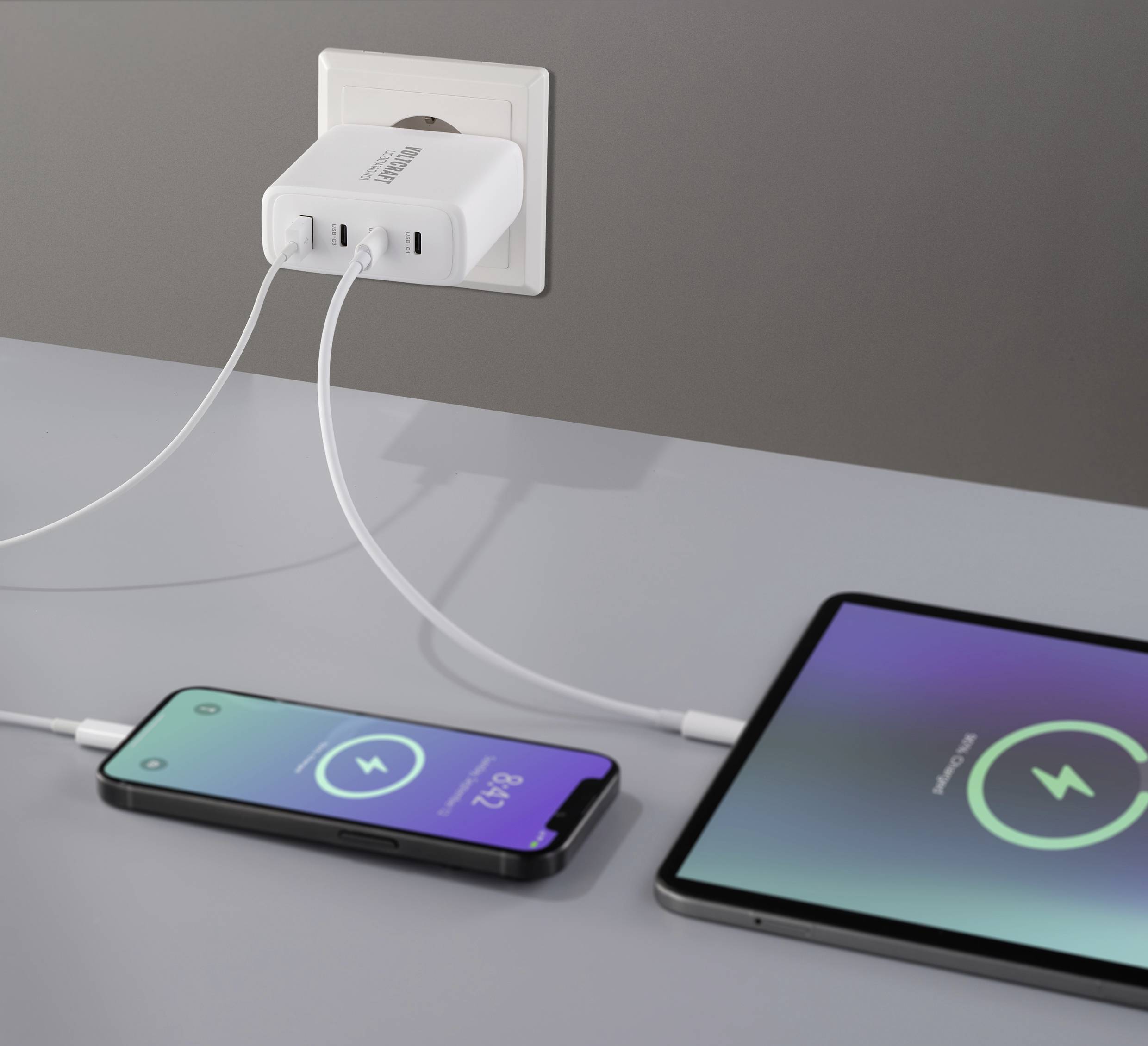 Nabíječka s dvěma připojenými smartphony zobrazuje na displejích nabíjecí ikony, které signalizují probíhající nabíjení.