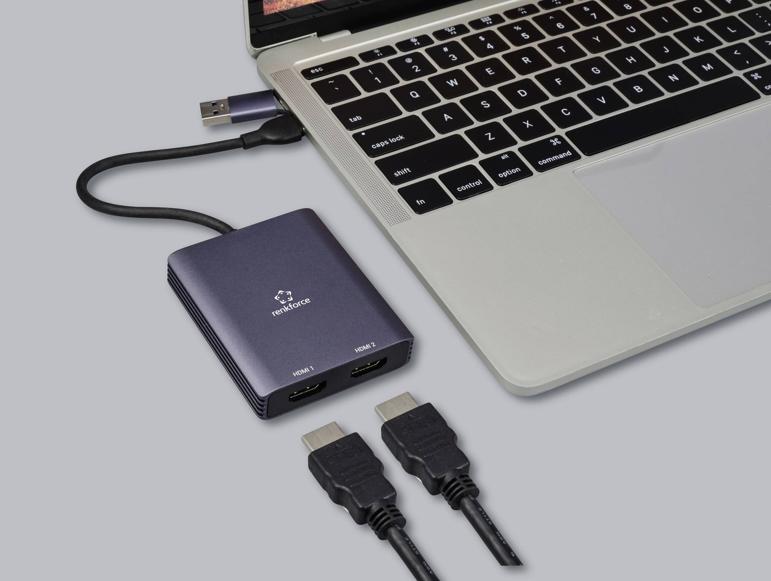 Notebook je připojen k HDMI rozdělovači, který má dva HDMI výstupy. Vedle jsou připraveny dva HDMI kabely.