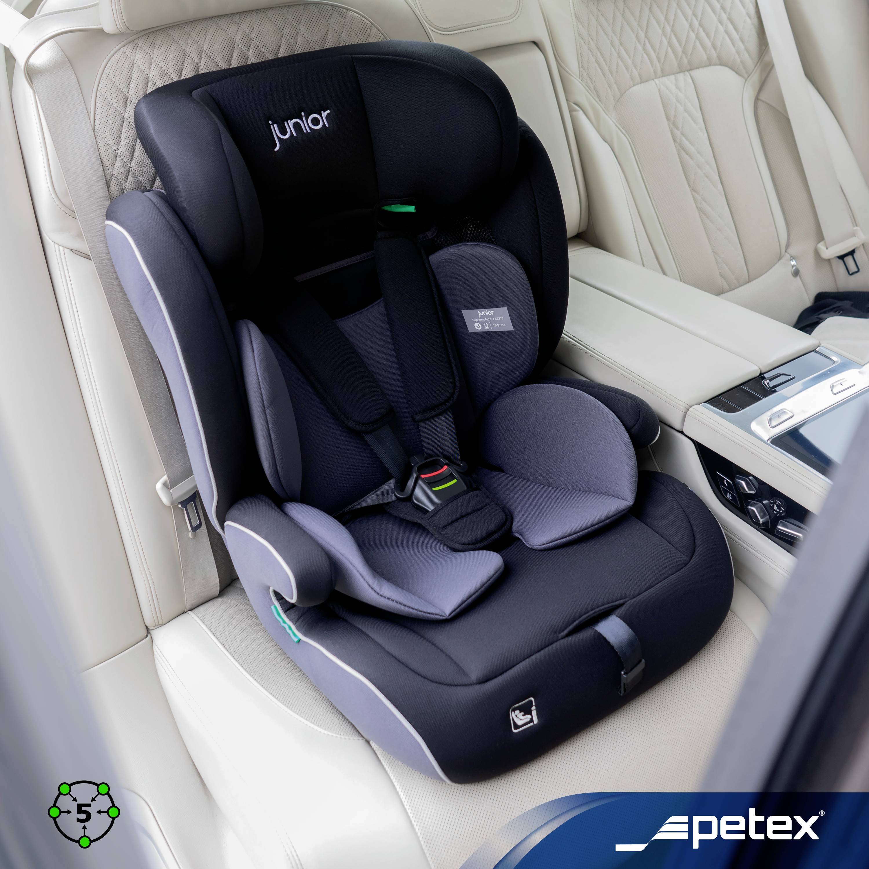 Dětská autosedačka značky Junior, model Petex, namontovaná na béžovém sedadle automobilu, zobrazená v interiéru vozidla s bezpečnostními pásy.