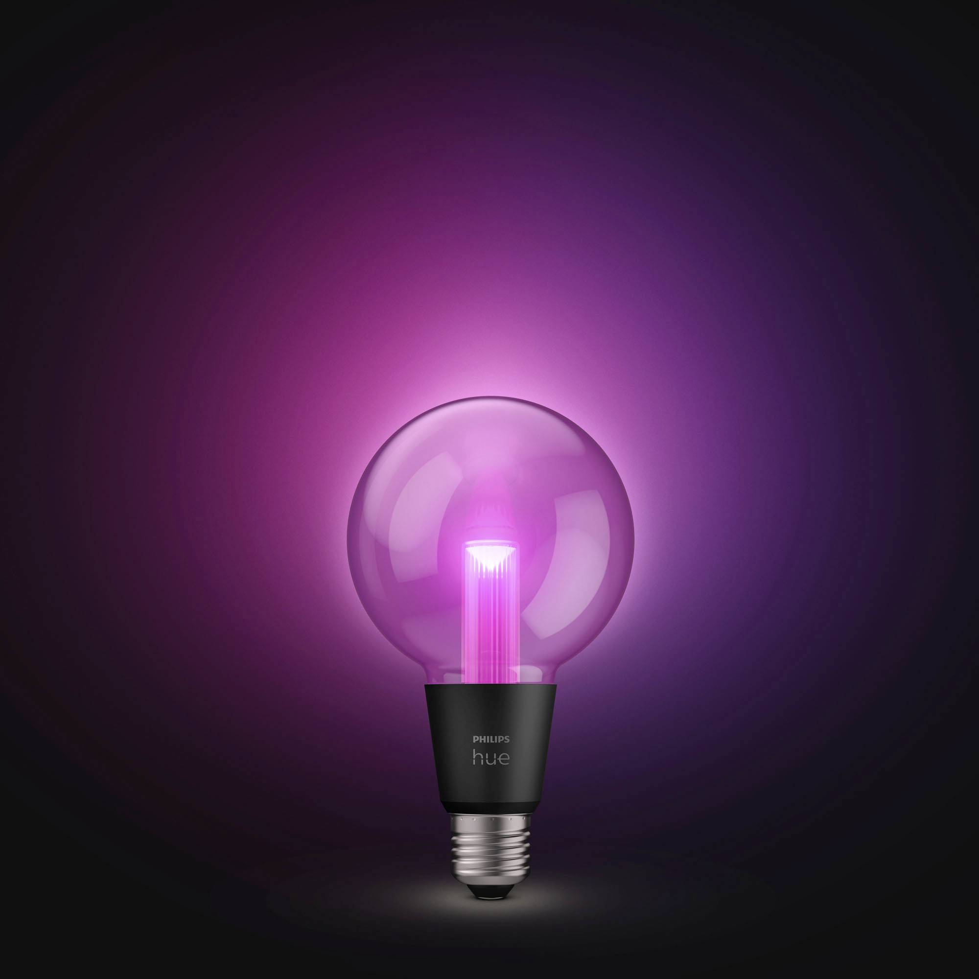 Žhnoucí, růžová žárovka značky Philips Hue před černým pozadím, která vyzařuje moderní a atmosférické světlo.