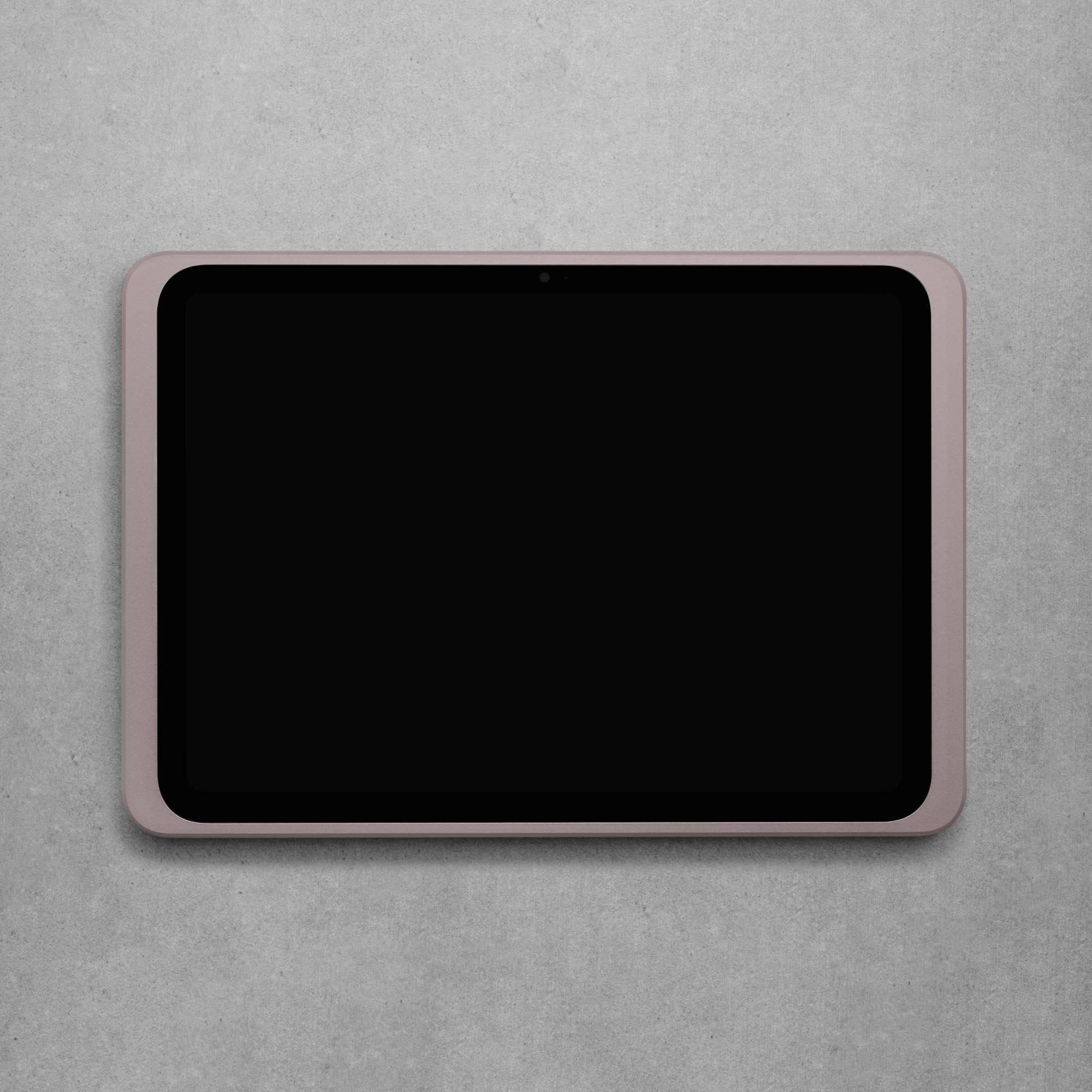 Tablet s růžovým rámečkem leží na šedém povrchu. Obrazovka je černá, bez viditelných aplikací nebo ikon.