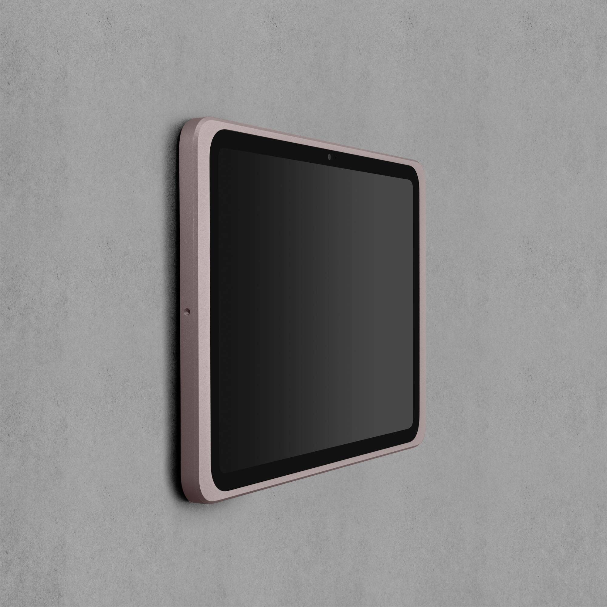 Tablet s kovovým rámečkem namontovaný na šedé betonové stěně, obrazovka je vypnutá, ukazuje štíhlý a moderní design.