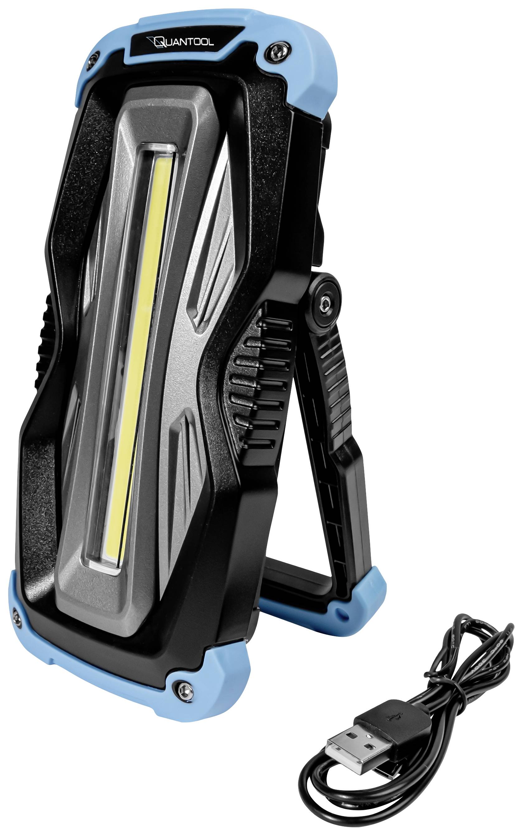 Modročerný přenosný LED reflektor se sklopným stojanem. Vedle něj leží USB nabíjecí kabel.