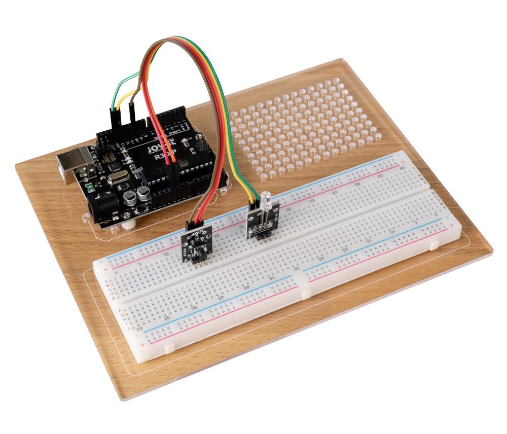 Deska Arduino připojená k nepájivému poli na dřevěné podložce, vhodná pro elektronické kutilské projekty.