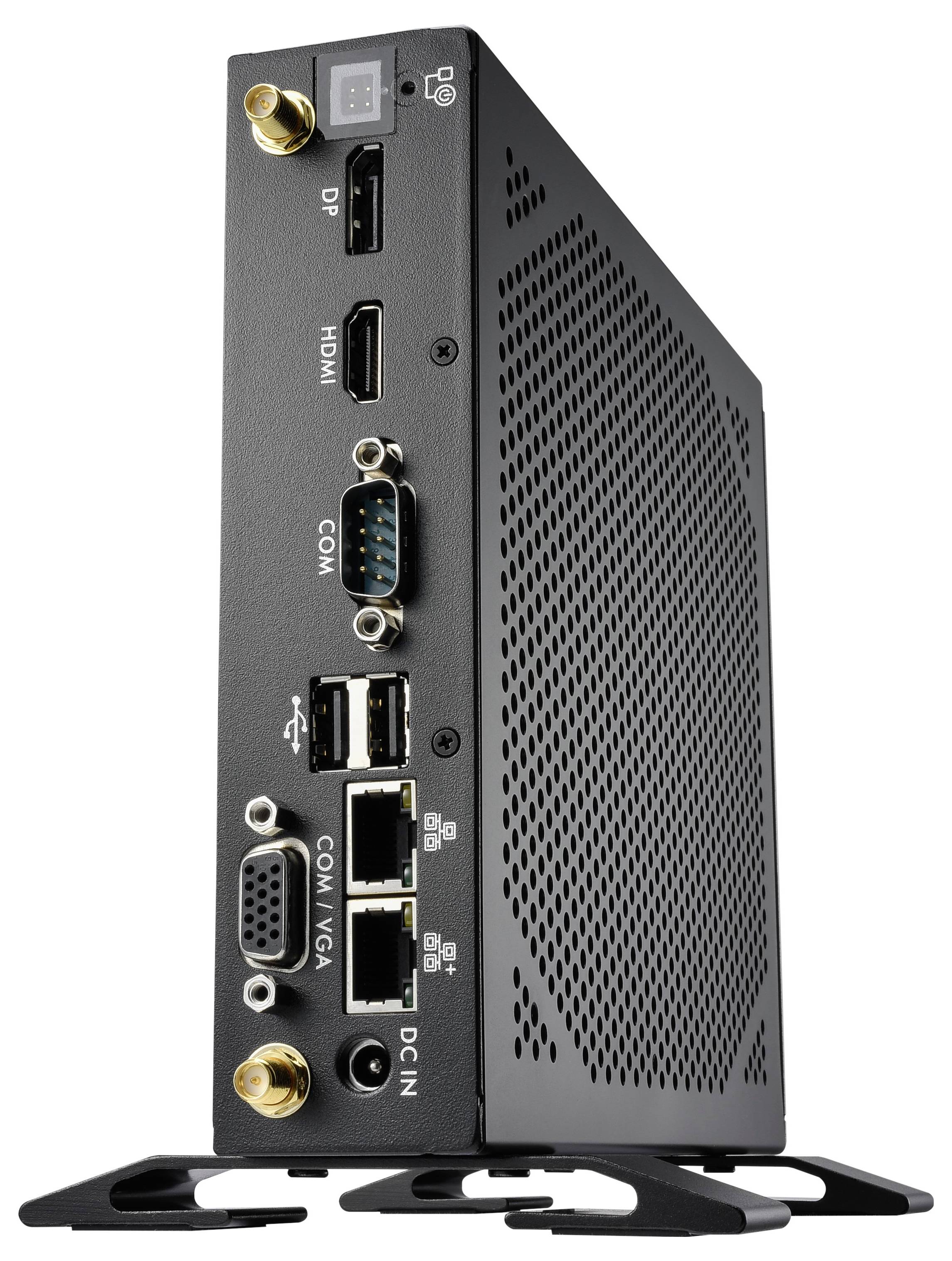 Černý mini počítač stojí ve svislé poloze. Viditelné porty jsou DP, HDMI, COM, USB, LAN, VGA a DC-IN. Zařízení má větrací štěrbiny.