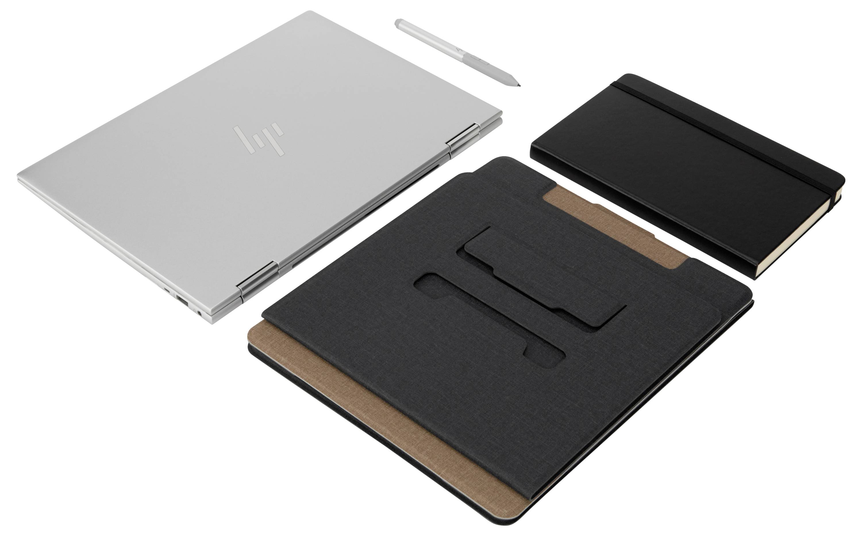Stříbrný laptop, pero a dva černé notes, uspořádané na stole. Příslušenství pro kreativní práci.