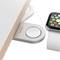 Apple Watch je nabíjena na magnetické nabíjecí stanici na světlém dřevěném stole.