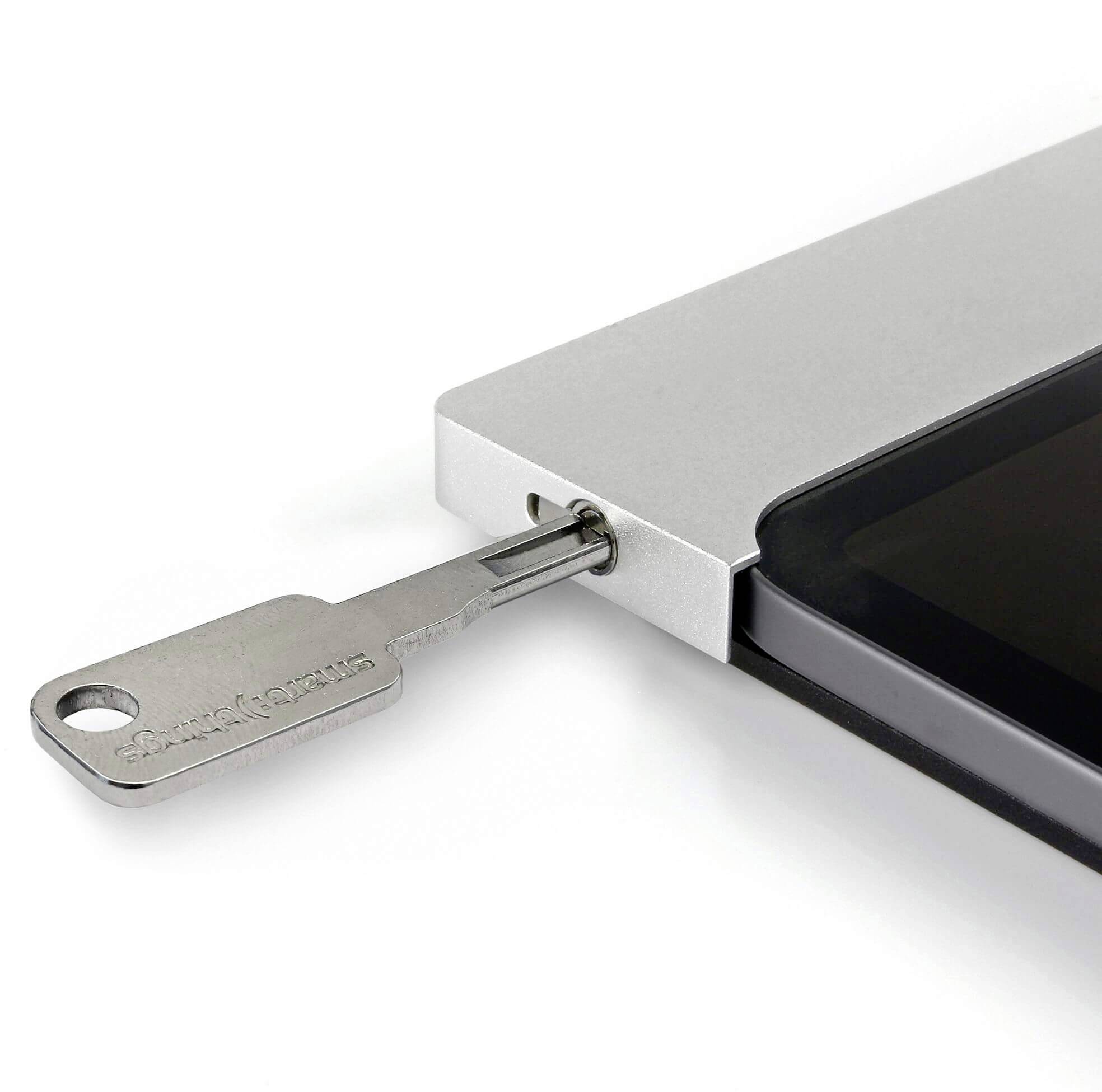 Stříbrná bezpečnostní zámka zajišťuje černý tablet v dokovací stanici.