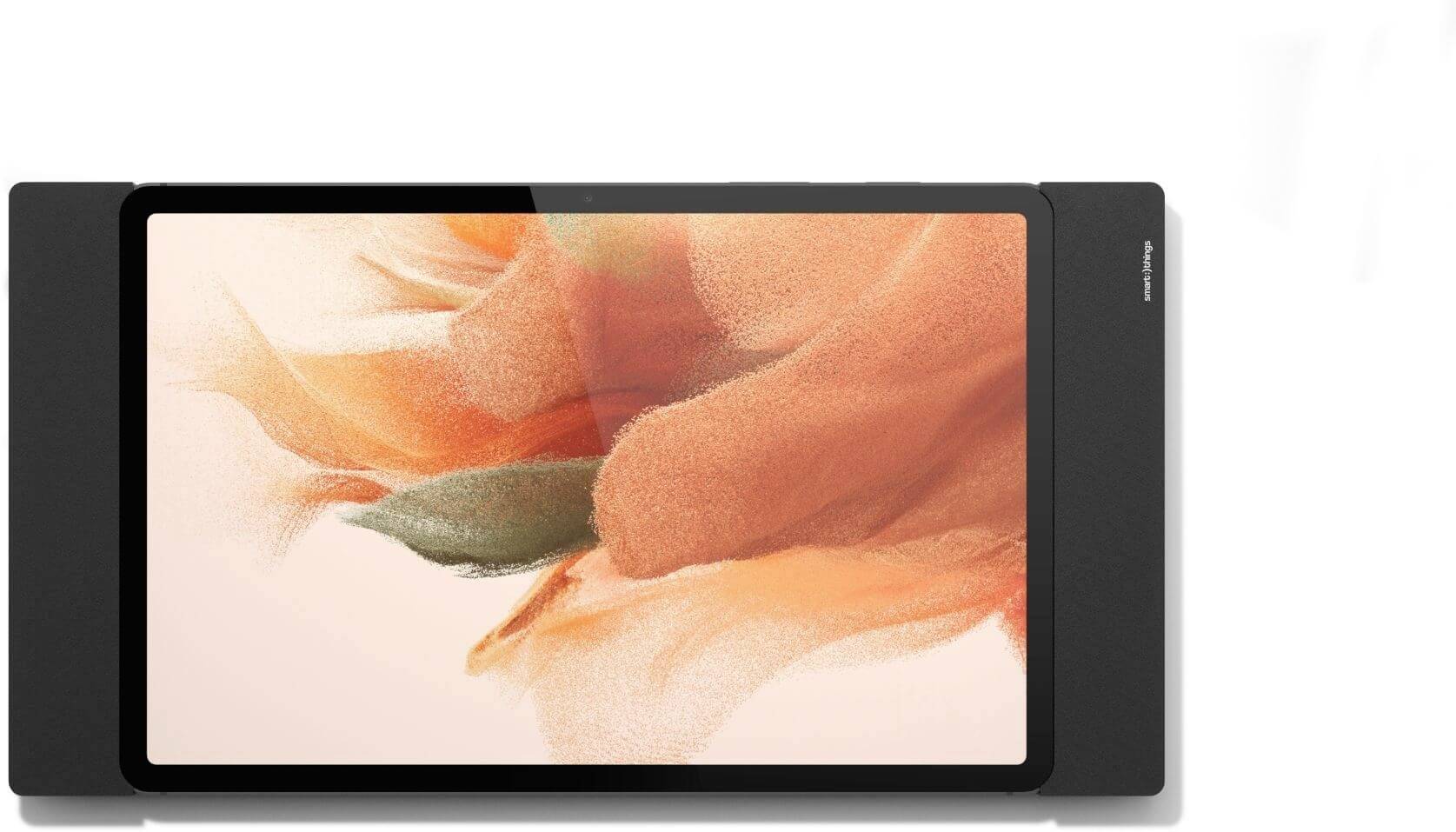 Tablet s digitálním abstraktním uměleckým displejem v oranžových a zelených tónech, obklopené černými reproduktory po obou stranách.