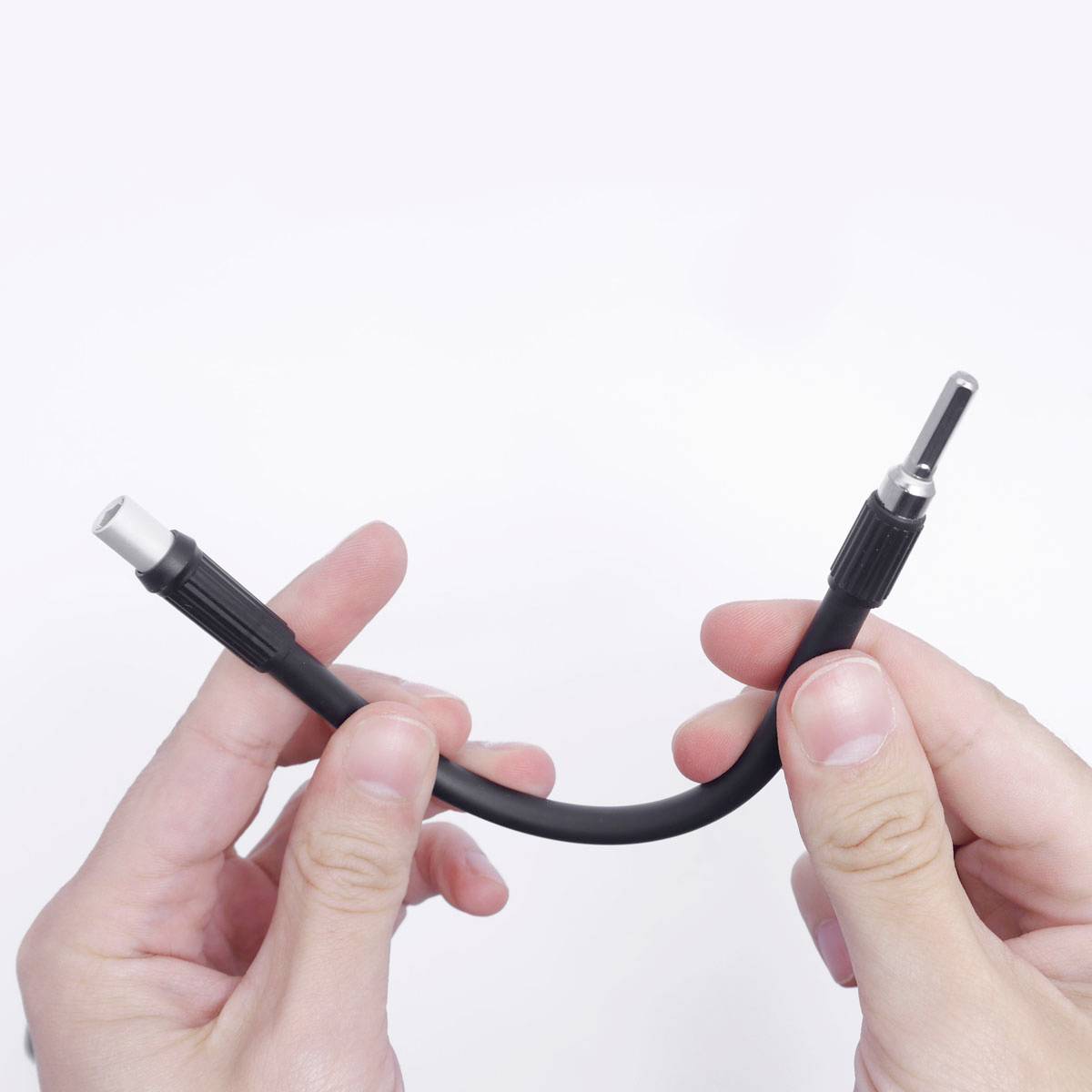 Ruce drží černý audio kabel s dvěma kovovými konektory.