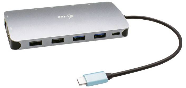 Stříbrný USB-C hub s více porty, včetně USB-A, USB-C a HDMI. Kabely připojené na pravé straně.