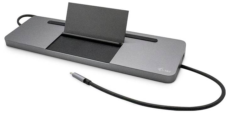 Šedý dokovací systém pro tablet s kabelem a zástrčkou. Má vzpřímený stojan určený pro tablet.