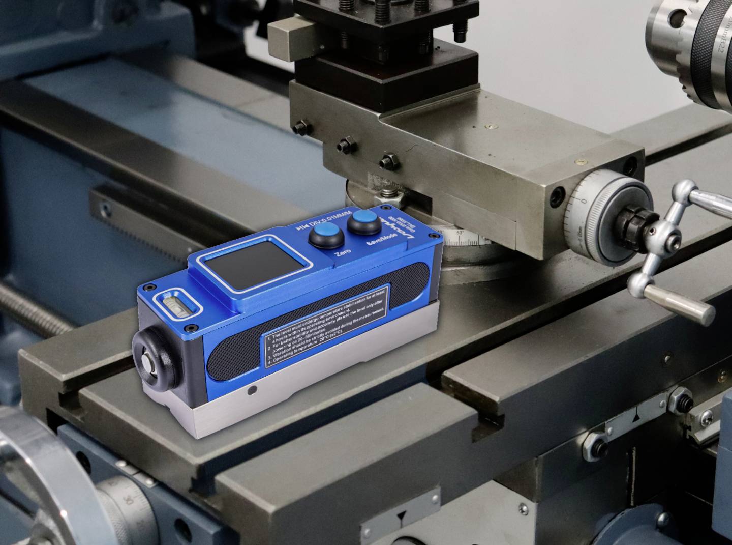 Modrý laserový zarovnávací nástroj umístěný na povrchu přesného stroje, který označuje použití pro zarovnání nebo měření v mechanickém prostředí.