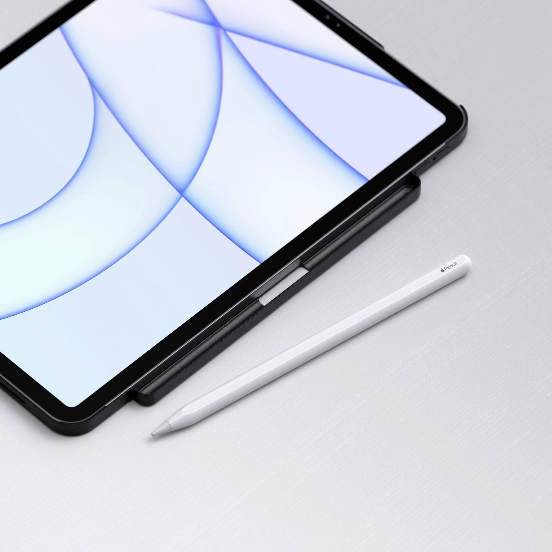 Tablet s bílou obrazovkou leží na šedém povrchu, vedle něj bílé pero.