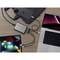 Několik zařízení, jako jsou smartphone, laptop a tablet, je propojeno centrálním USB hubem, který leží na dřevěném stole.