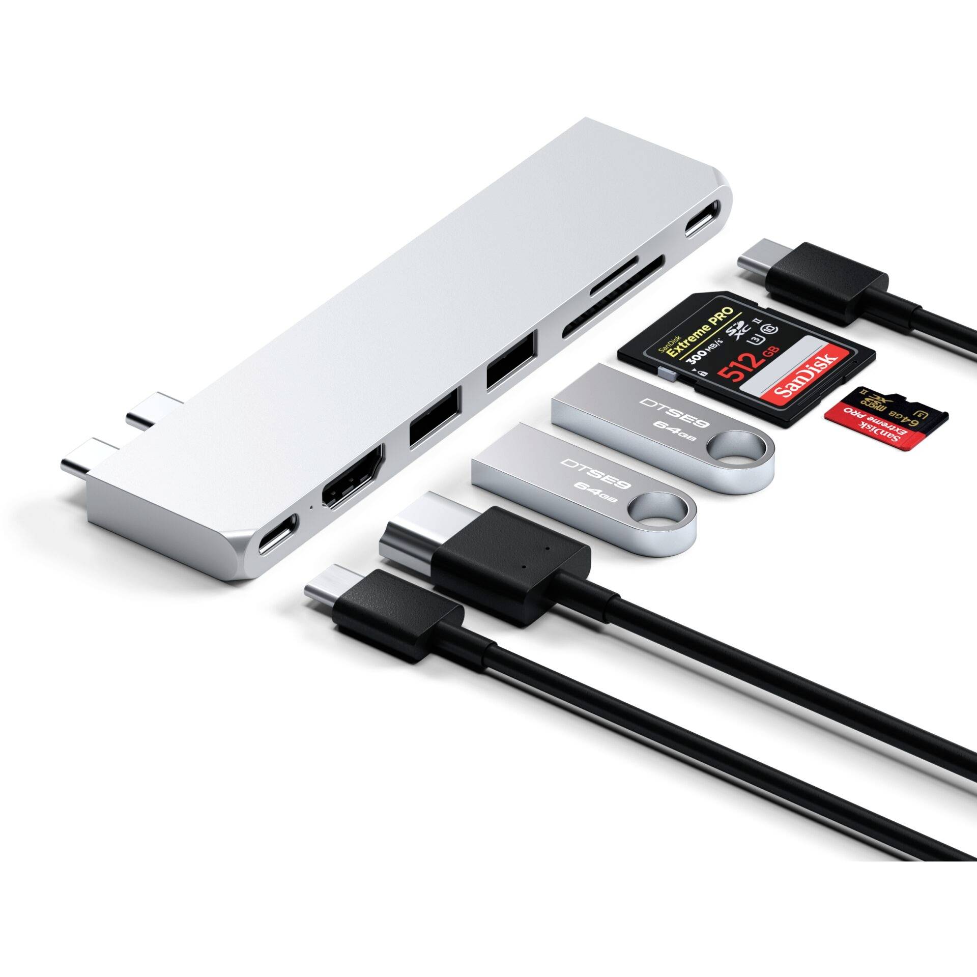 Stříbrný USB-C hub s HDMI, USB porty a čtečkami karet, obklopený různými USB flash disky a paměťovými kartami.