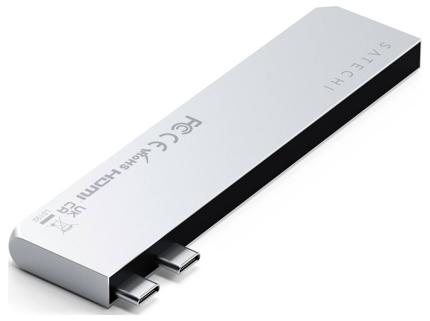 Stříbrný USB-C hub se dvěma porty na jedné straně, položený na bílém pozadí. Viditelný název značky 'SATECHI'.