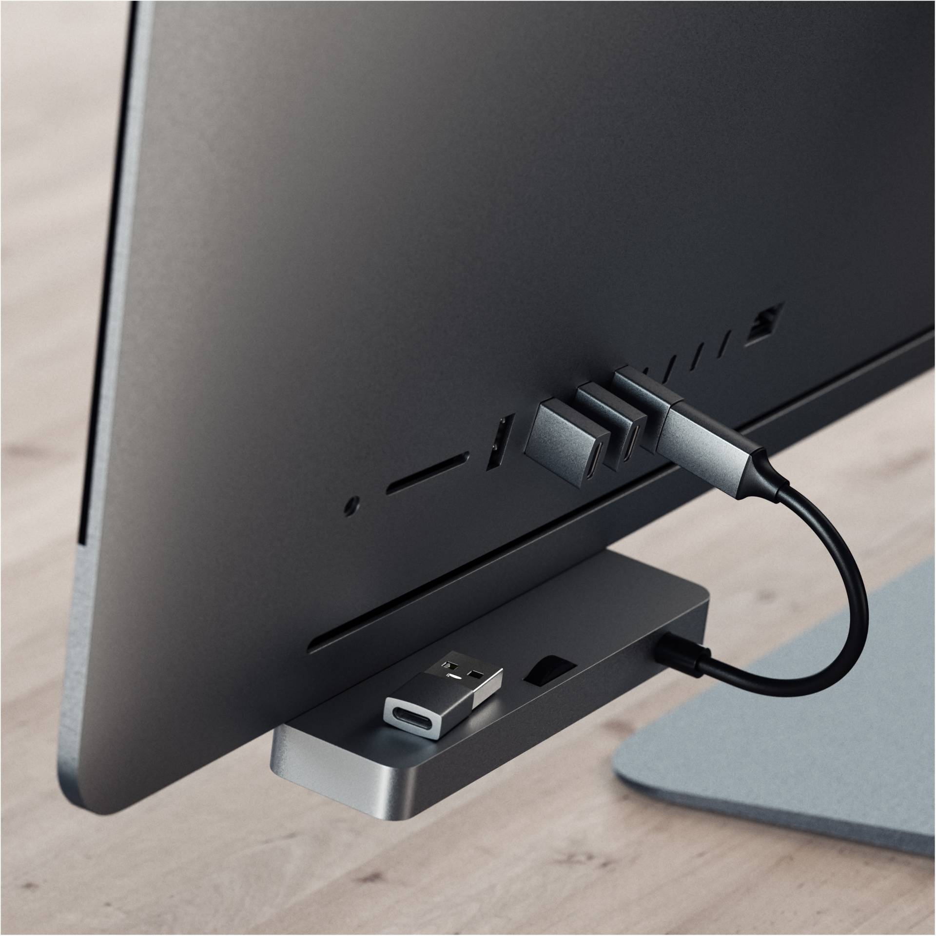 Počítač stojí na stole. Na zadní straně jsou různé konektory a USB kabel zapojen do rozbočovače.
