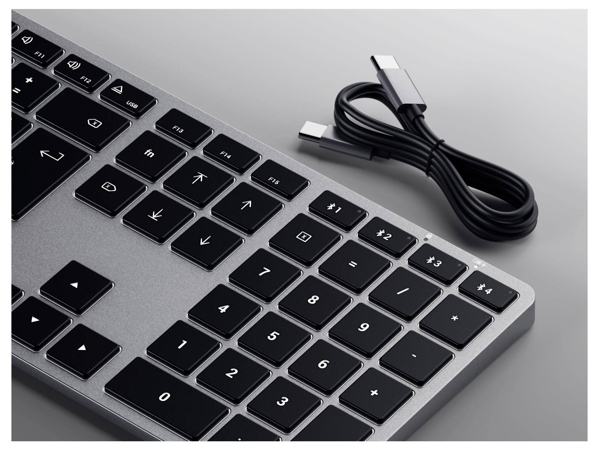 Klávesnice s černošedými klávesami a odpojeným USB kabelem.