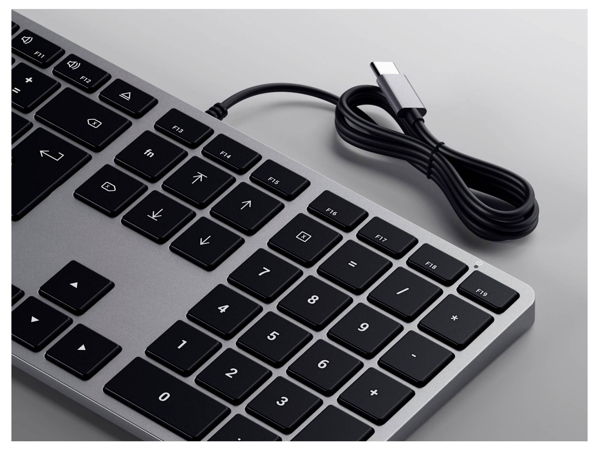 Černá klávesnice s numerickou klávesnicí, připojená přes USB kabel. Rozložení zahrnuje funkční klávesy a numerický blok.