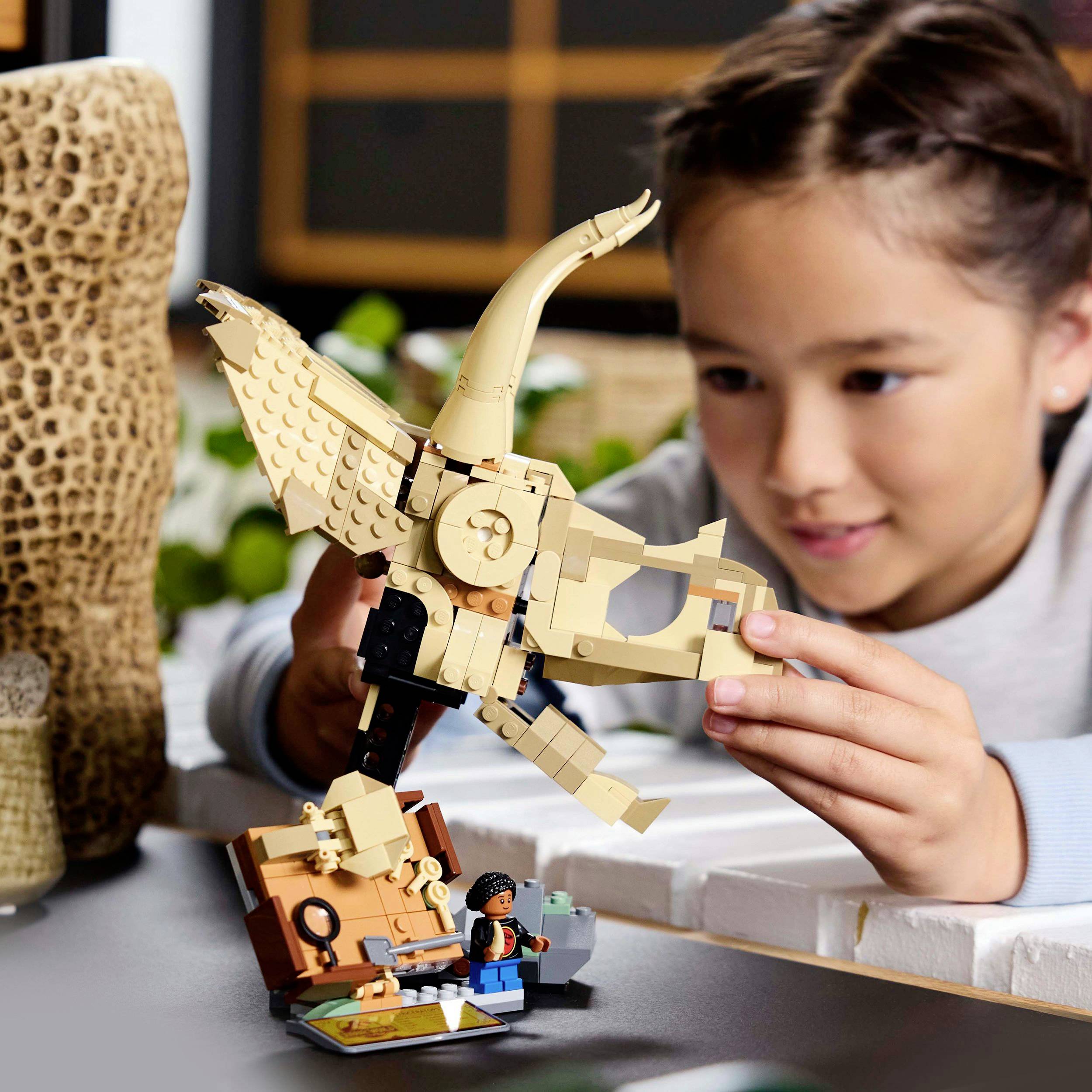 Dítě staví LEGO model zlatého ptáka. Soustředěně se dívá na kamínky, které skládá dohromady.