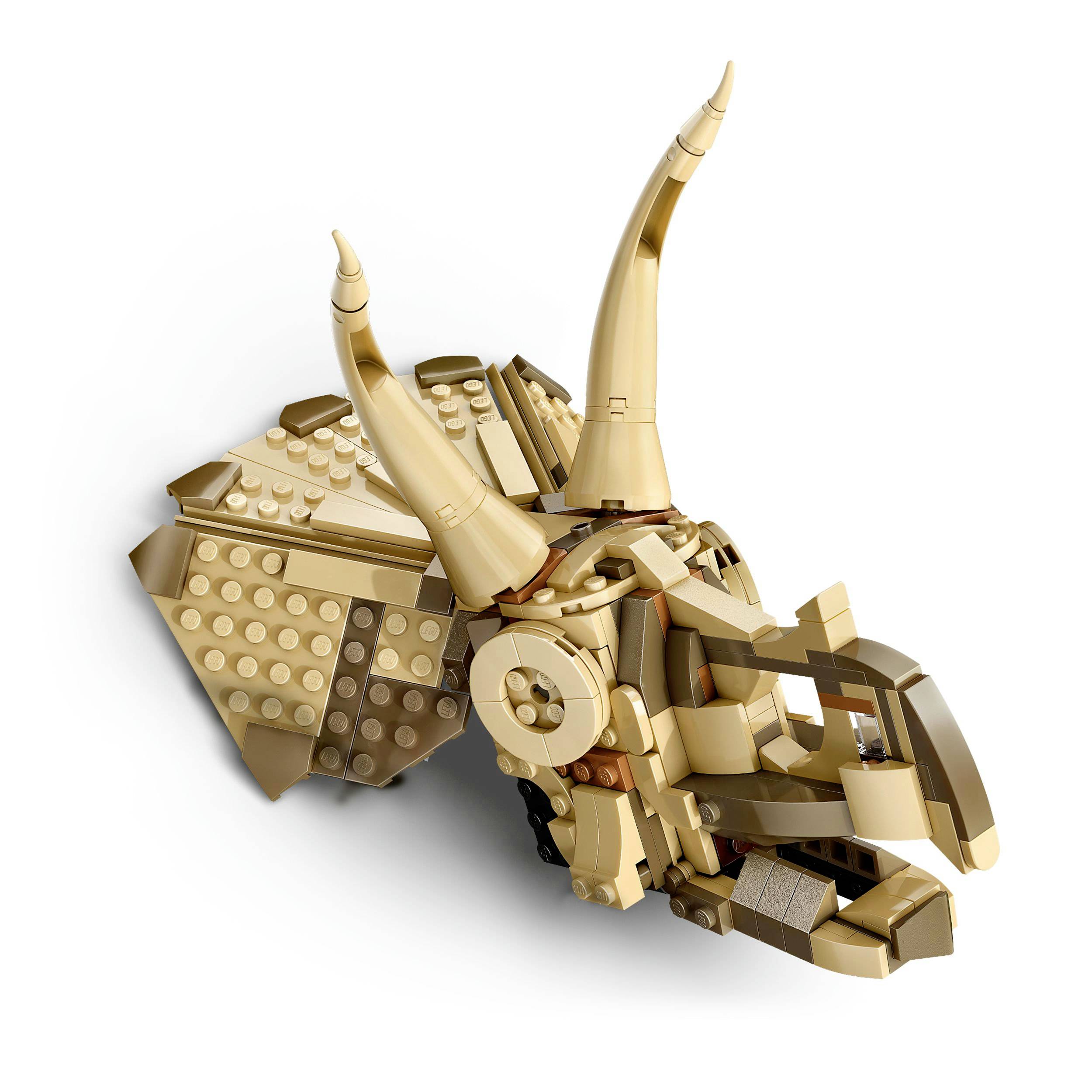LEGO model hlavy triceratopse v hnědých a béžových tónech, ležící na bílém pozadí.