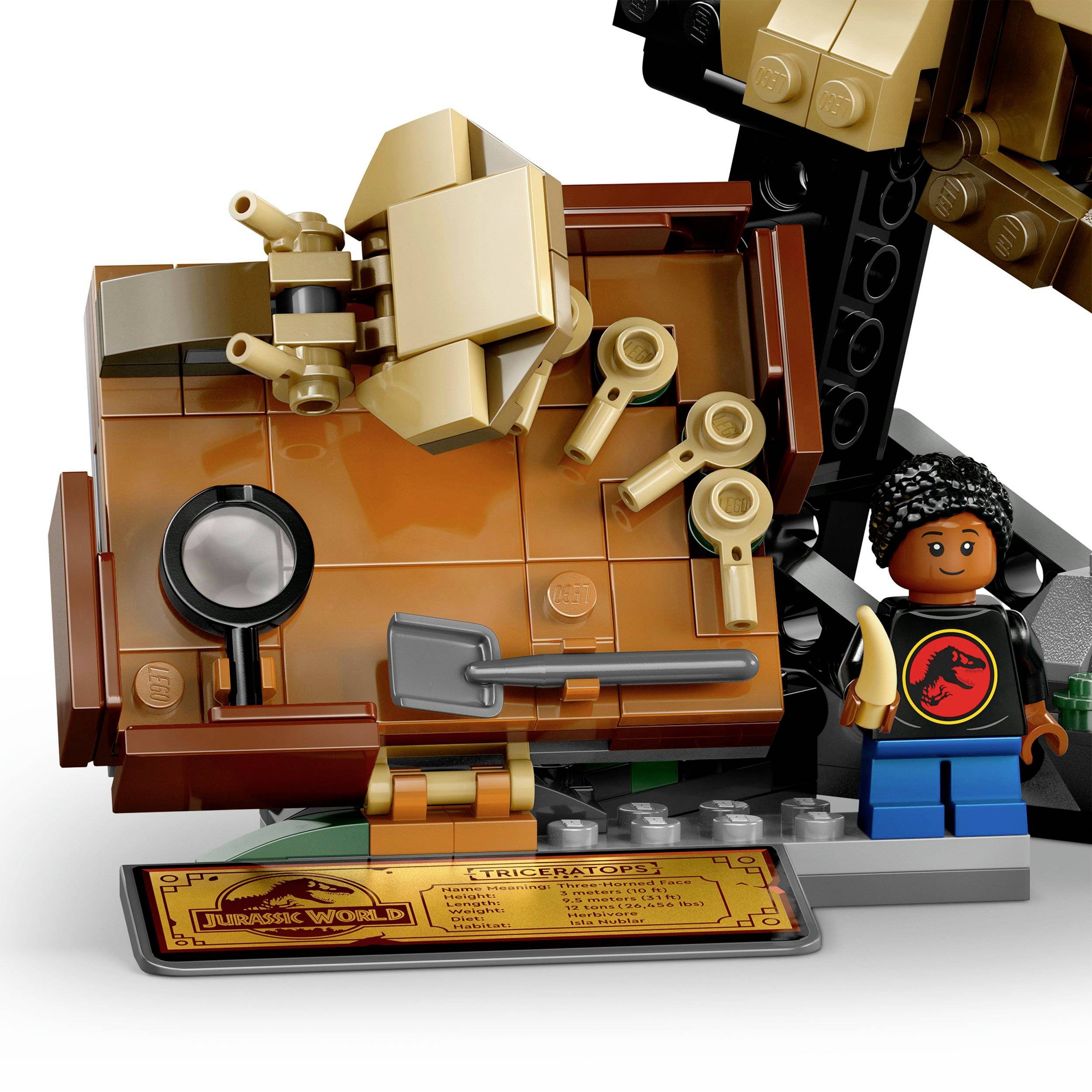 Model LEGO zobrazuje lebku triceratopse s minifigurkou a příslušenstvím, jako je lopata a lupa, umístěný na stavební podložce.