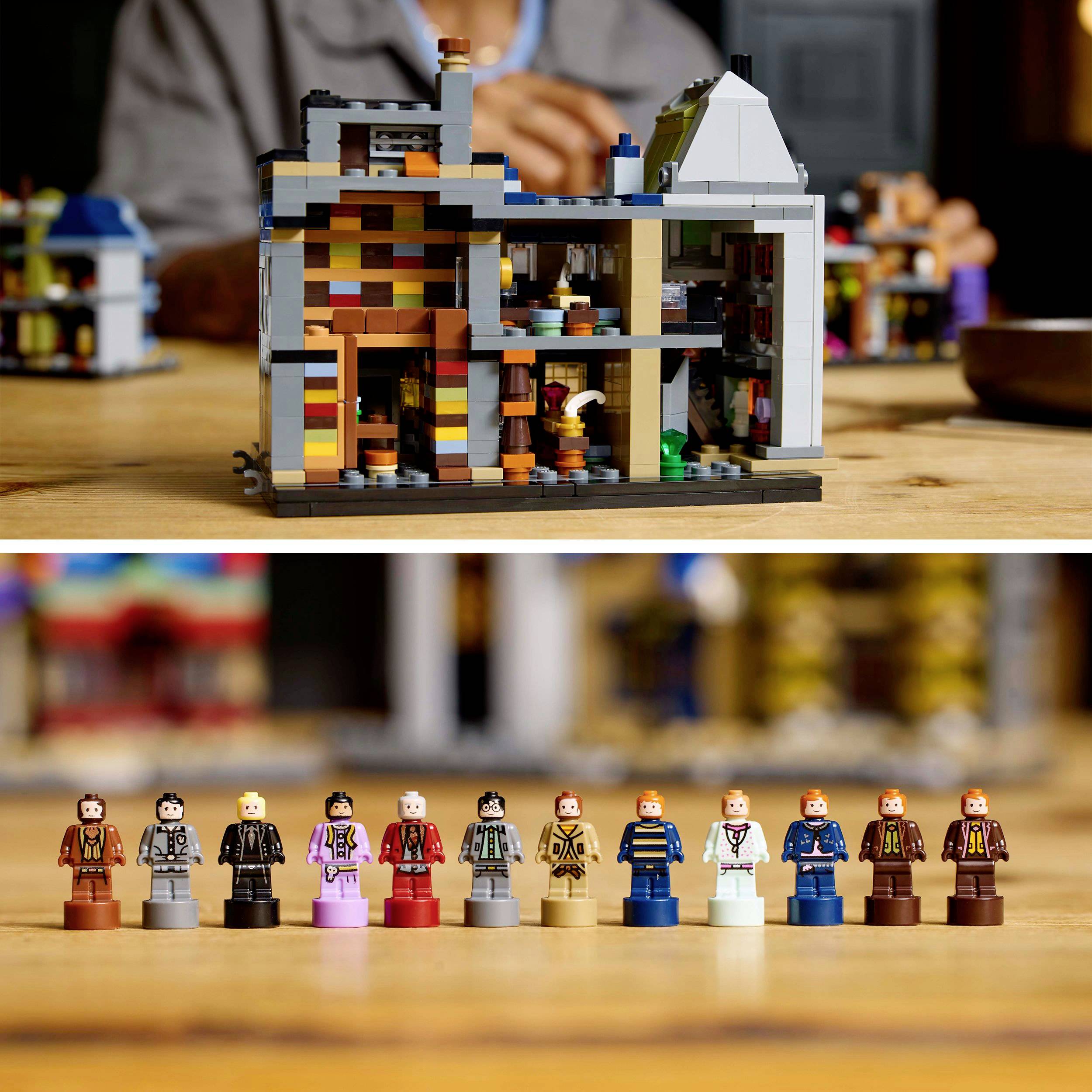 Lego model městského domu stojí na stole, pod ním je v řadě rozestavěno jedenáct barevně oblečených Lego figurek.