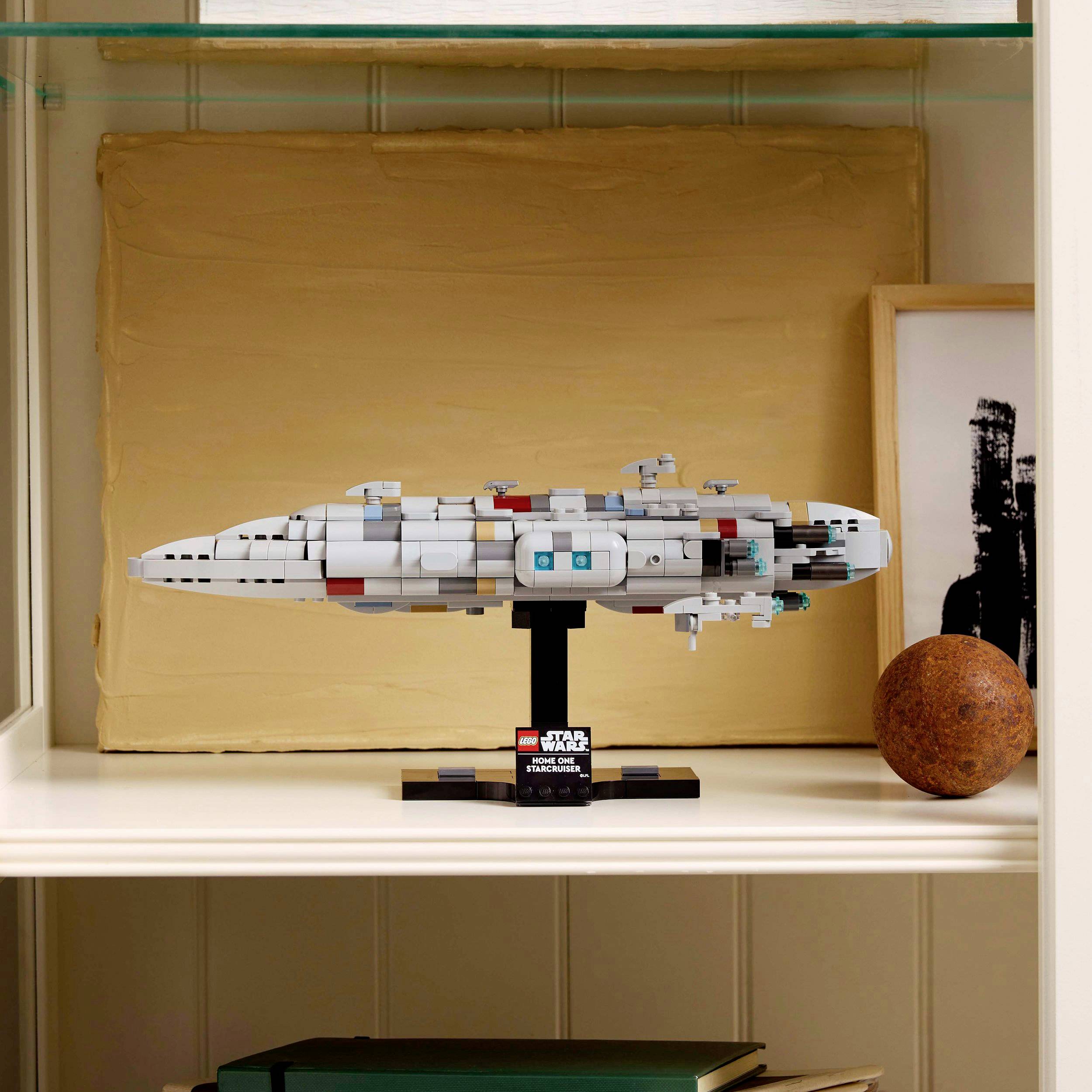 Model LEGO hvězdné lodi ze 'Star Wars' na poličce, obklopený knihami a dekoracemi.