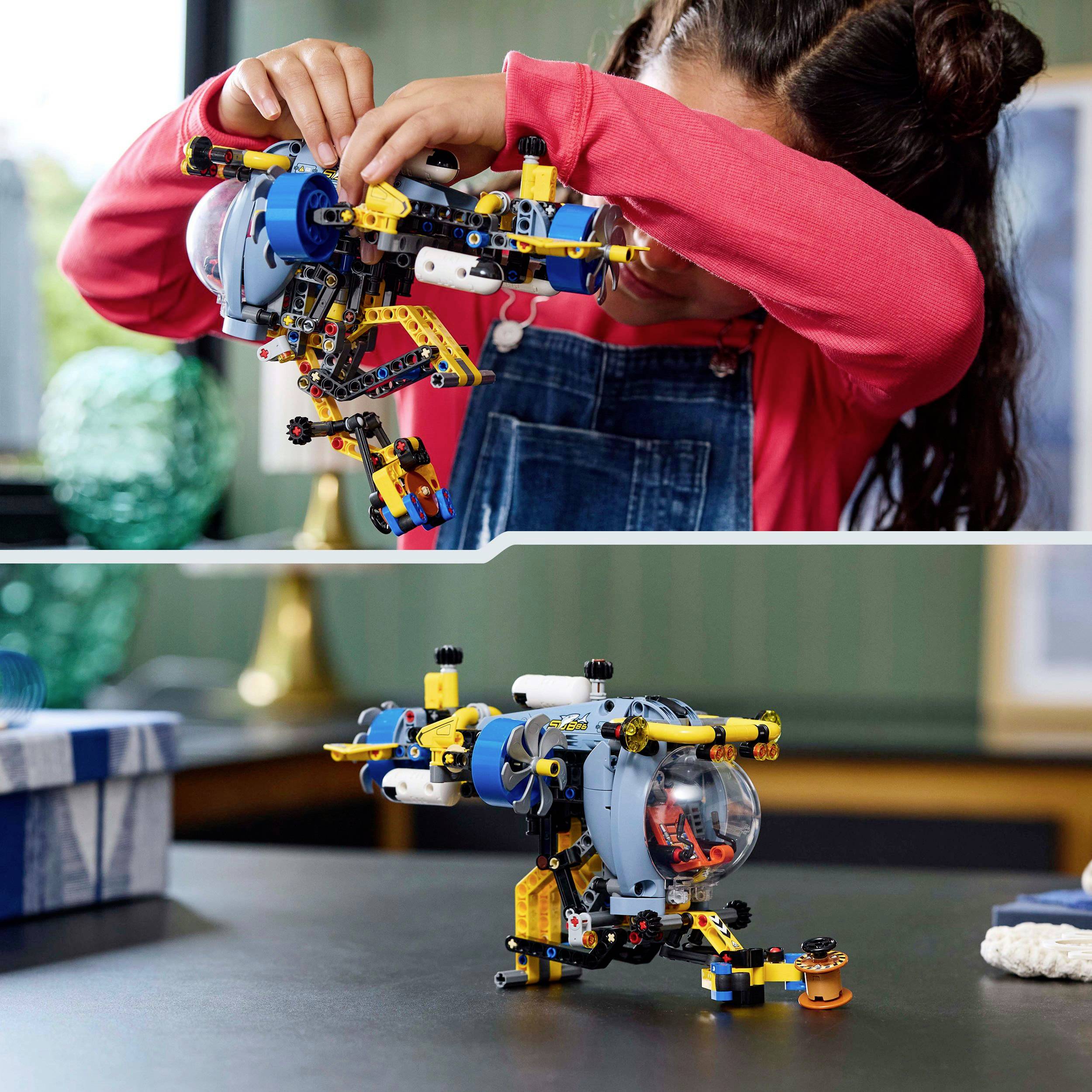 Dítě v červeném tričku staví robota z barevných stavebních kostek. V pozadí místnost s knihami a rostlinami.