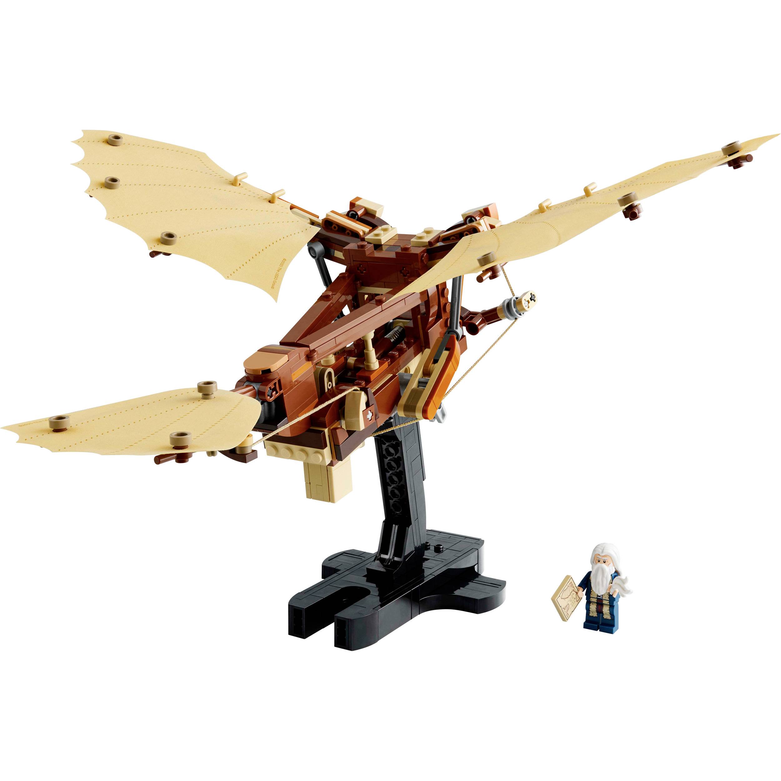 Model LEGO mechanického létajícího ptáka s roztaženými křídly, vedle něhož stojí malá figurka na podstavci.