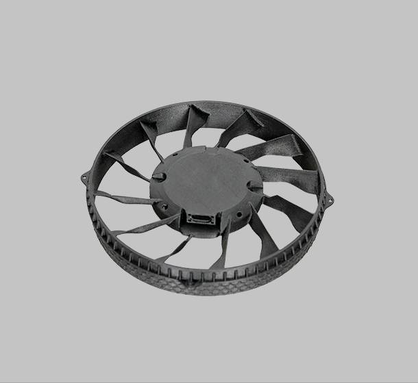 Černý kulatý ventilátor s několika lopatkami na šedém pozadí, vhodný pro chlazení nebo větrání.