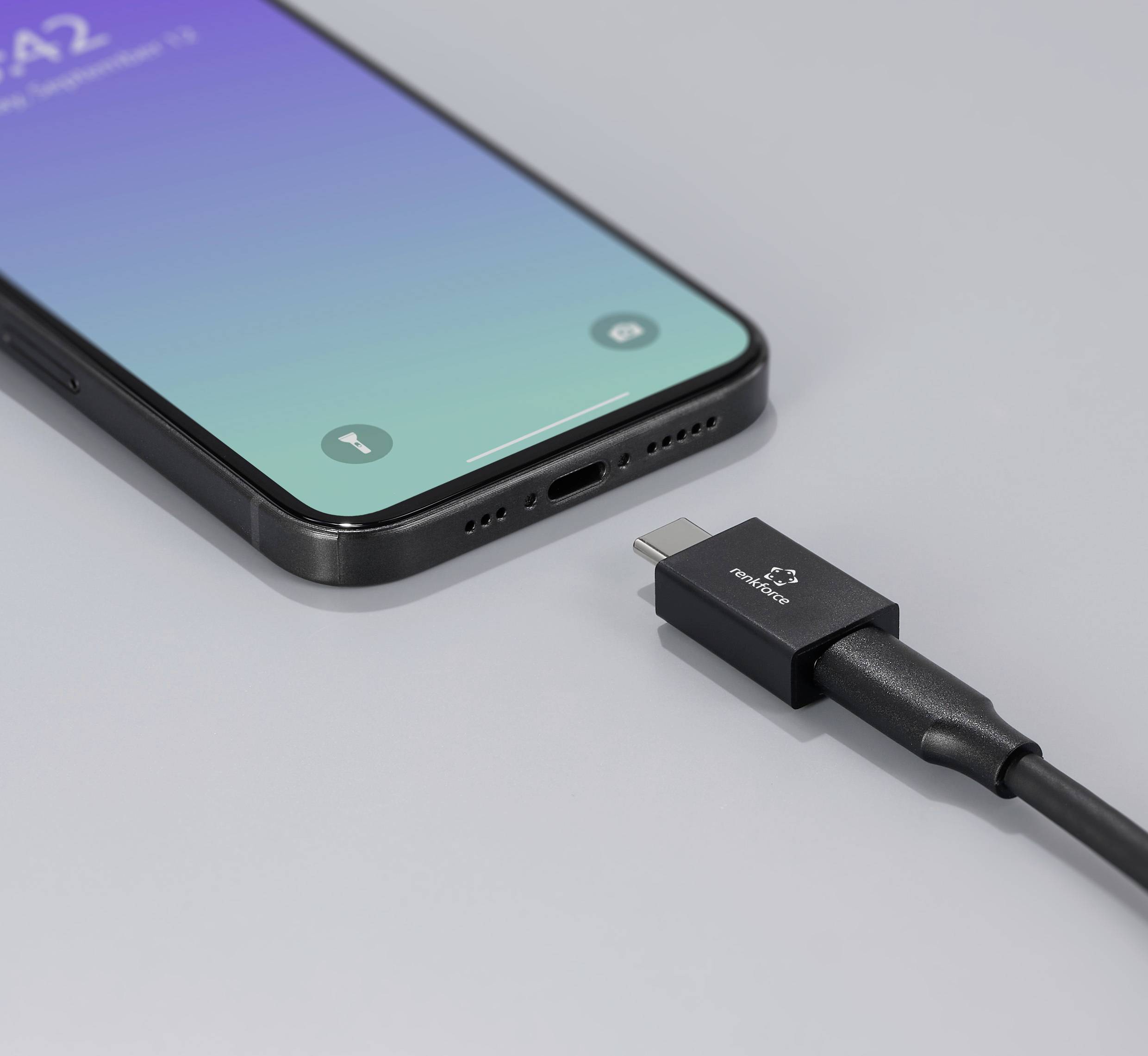 Smartphone s modro-zeleným displejem je připojeno nabíjecím kabelem USB-C.