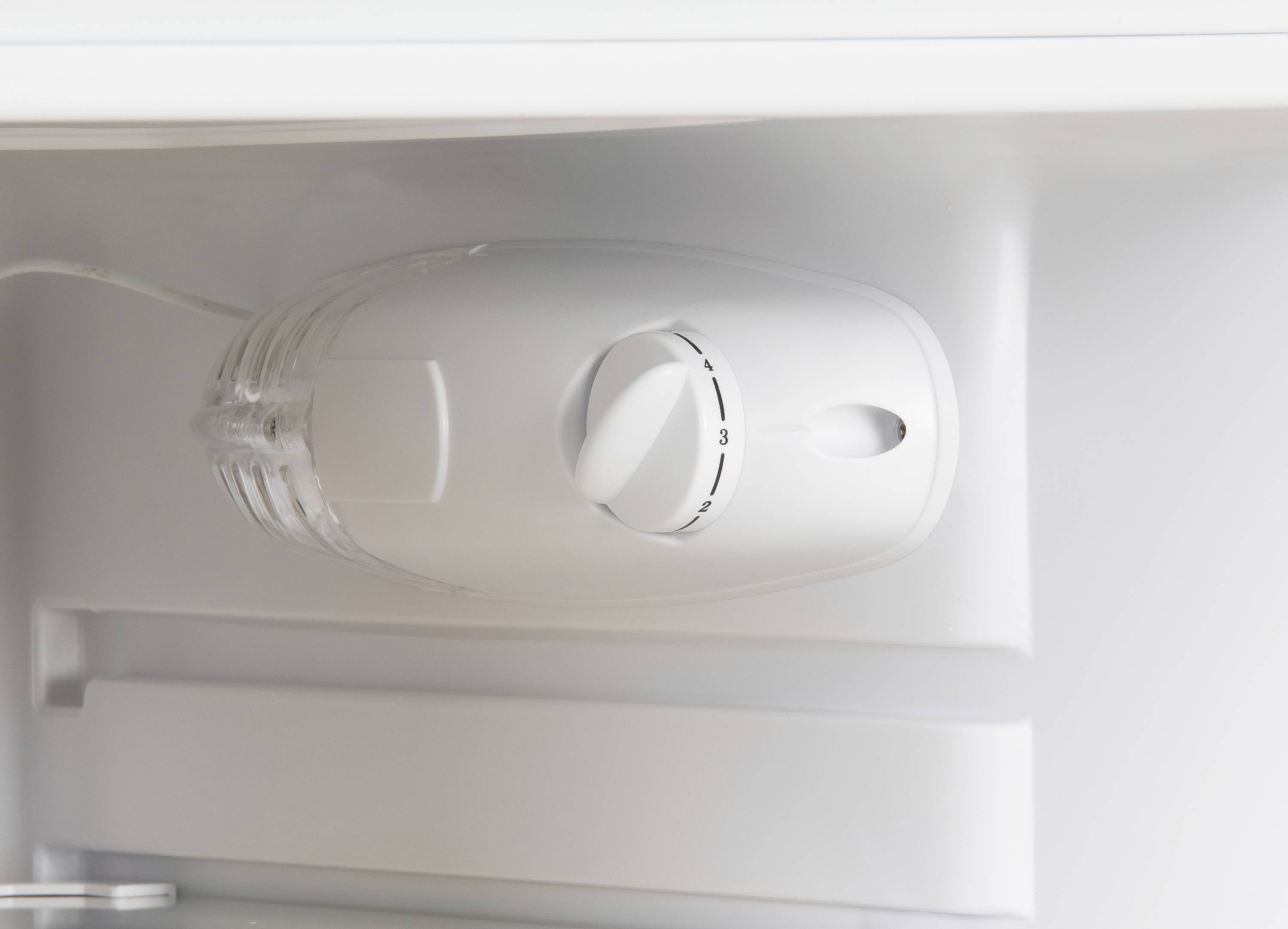 Detail chladničky ukazuje termostat s otočným regulátorem nastaveným do střední polohy.