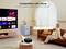 Žena sedící na gauči ovládá projektor hlasovým příkazem přes Alexu, který promítá streamovací služby na plátno.