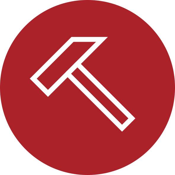 Bílá ikona kladiva v diagonále na červeném kruhovém pozadí, připomínající symbol nástroje nebo stavby.