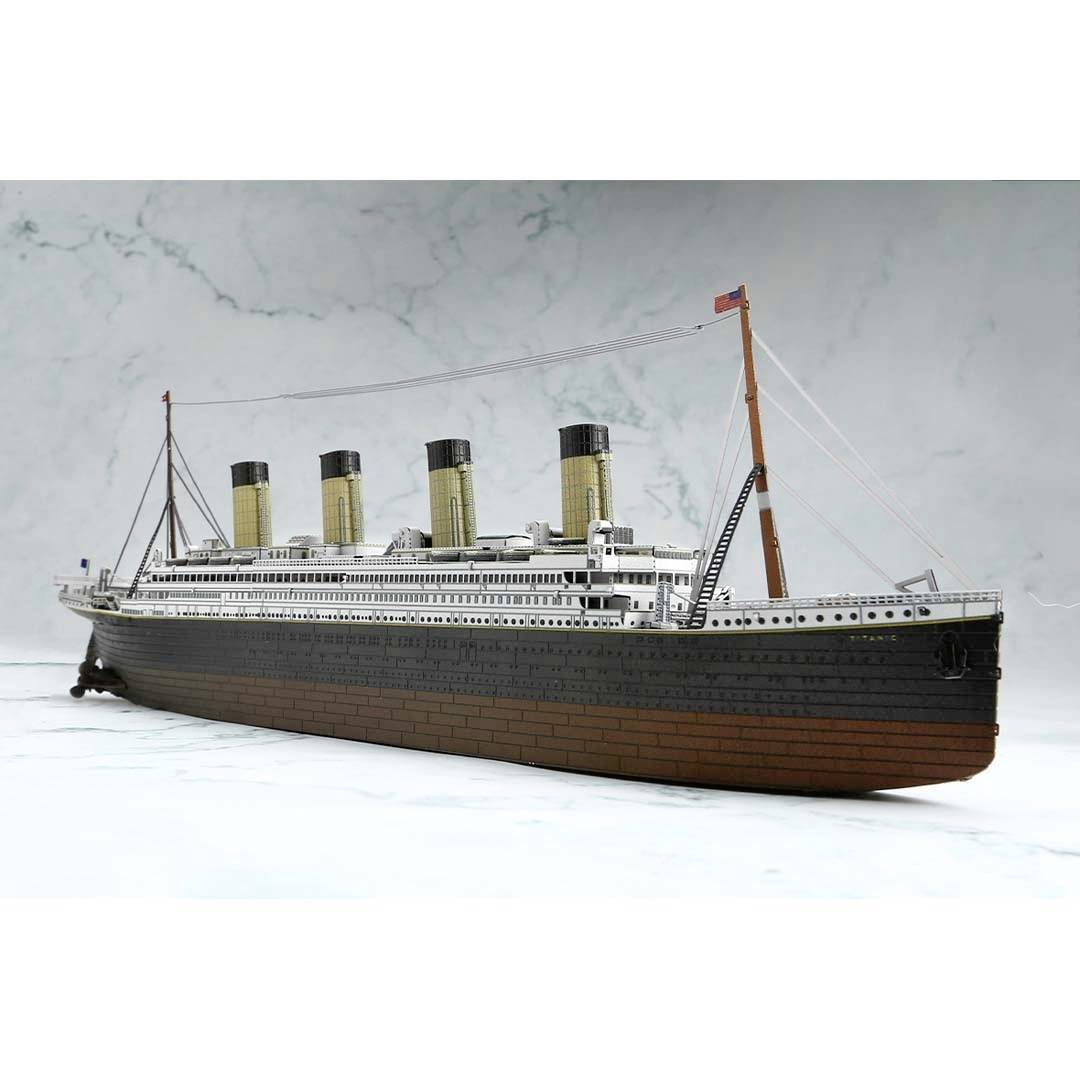 Detailní model Titanicu se čtyřmi komíny, umístěný na mořském pozadí.