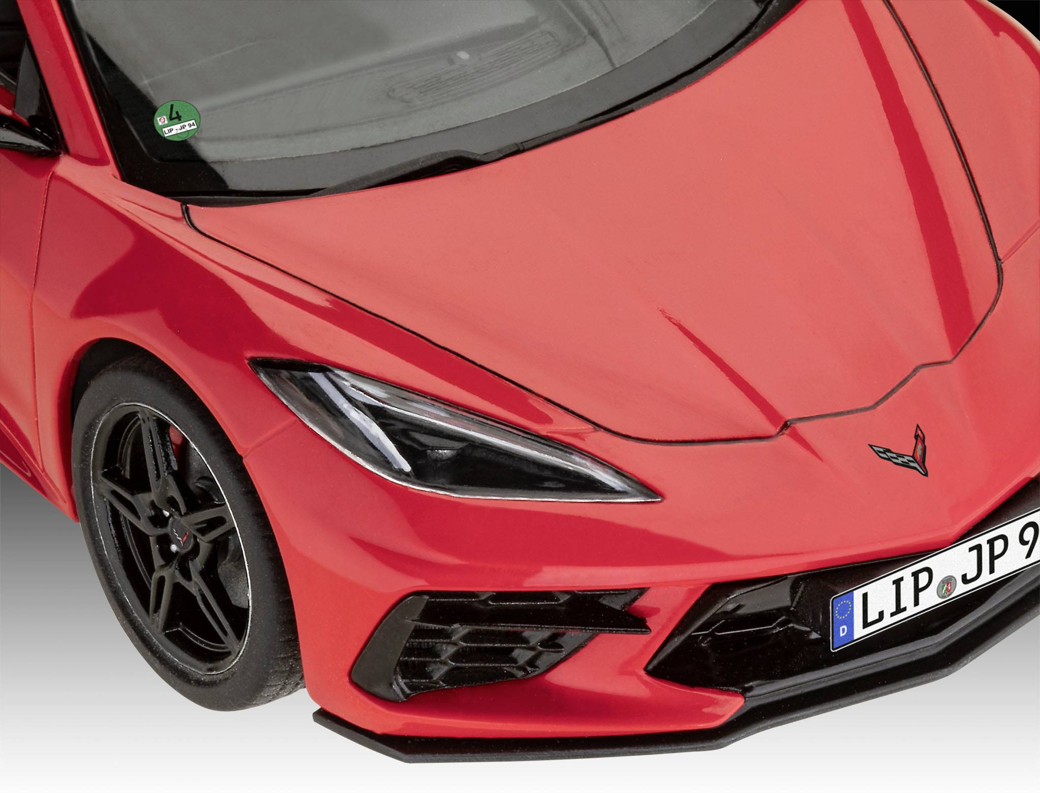 Červené sportovní auto fotografované zepředu, moderní design, černá kola, částečně viditelná registrační značka.