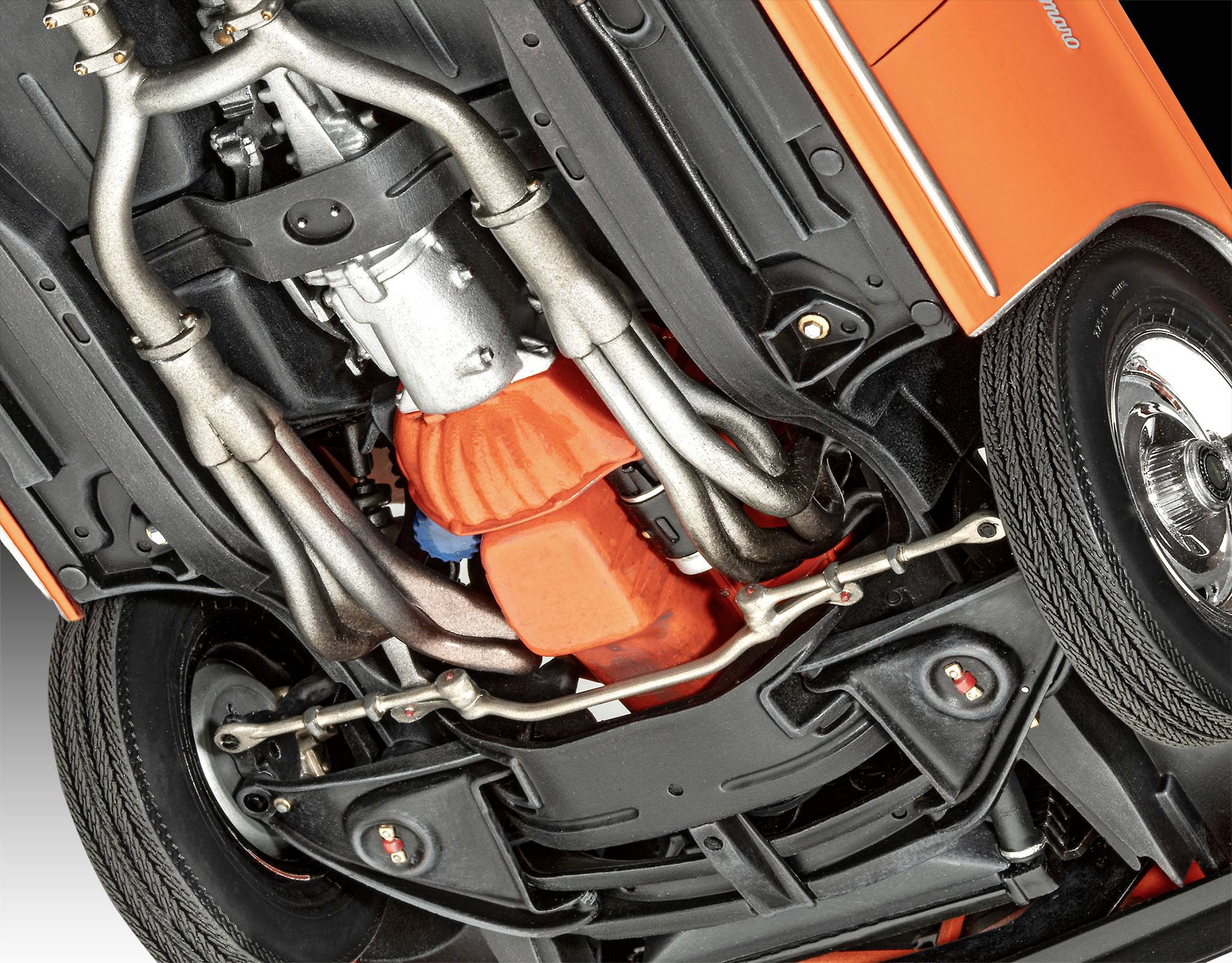 Pohled zespodu na oranžové auto s viditelným výfukem a mechanickými komponenty. Vozidlo je mírně nakloněné nahoru.