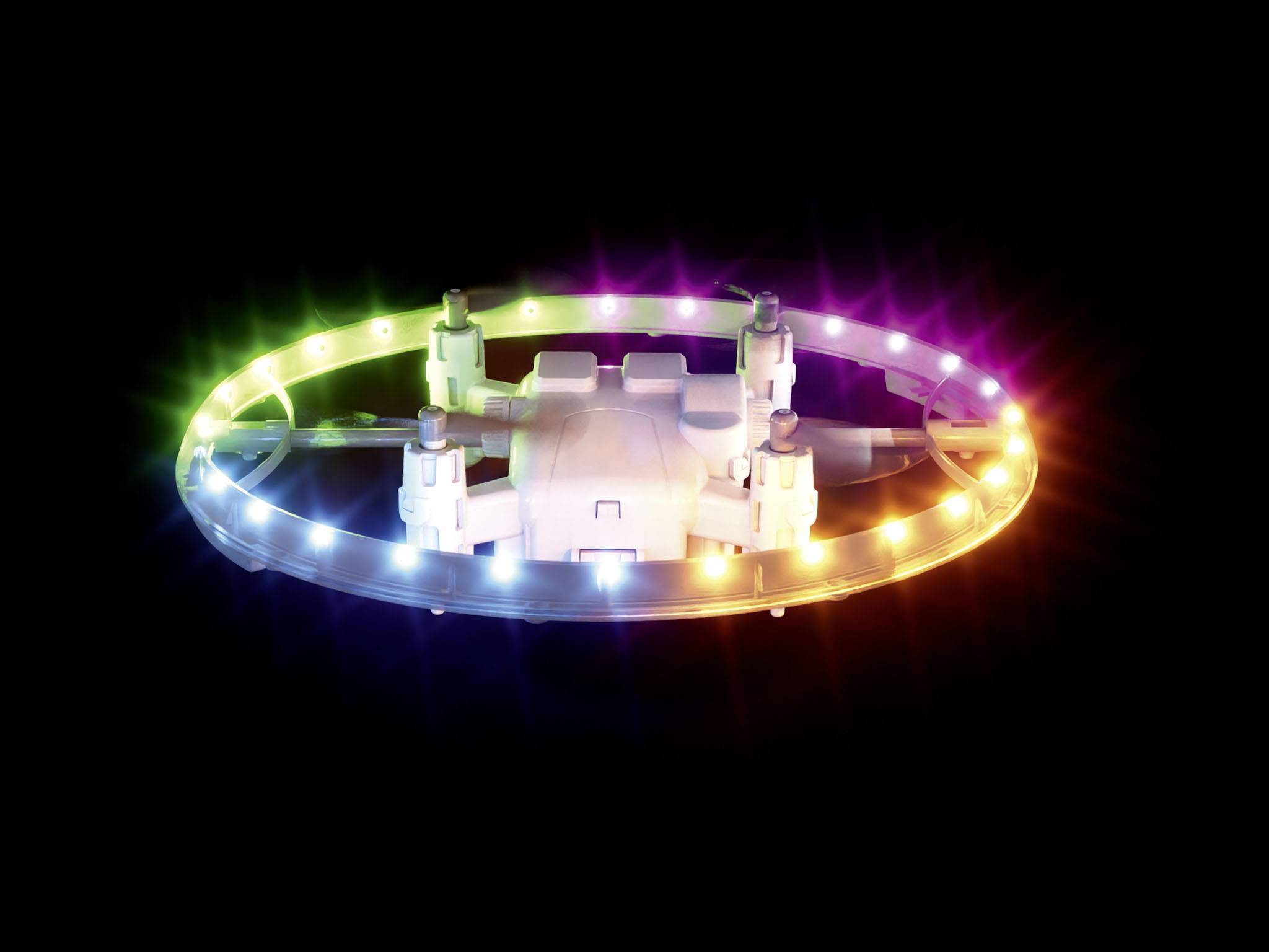 Vznášející se dron s osvětleným LED kroužkem v různých barvách na černém pozadí.