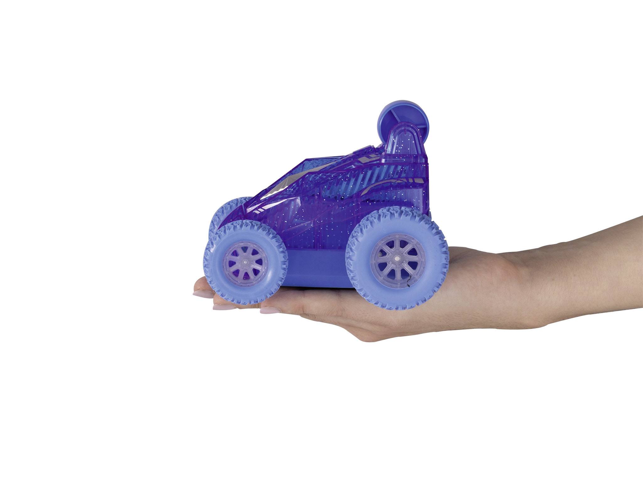 Ruka drží malé hračkové autíčko v lila-modré barvě s tlustými koly. Auto má futuristický design.