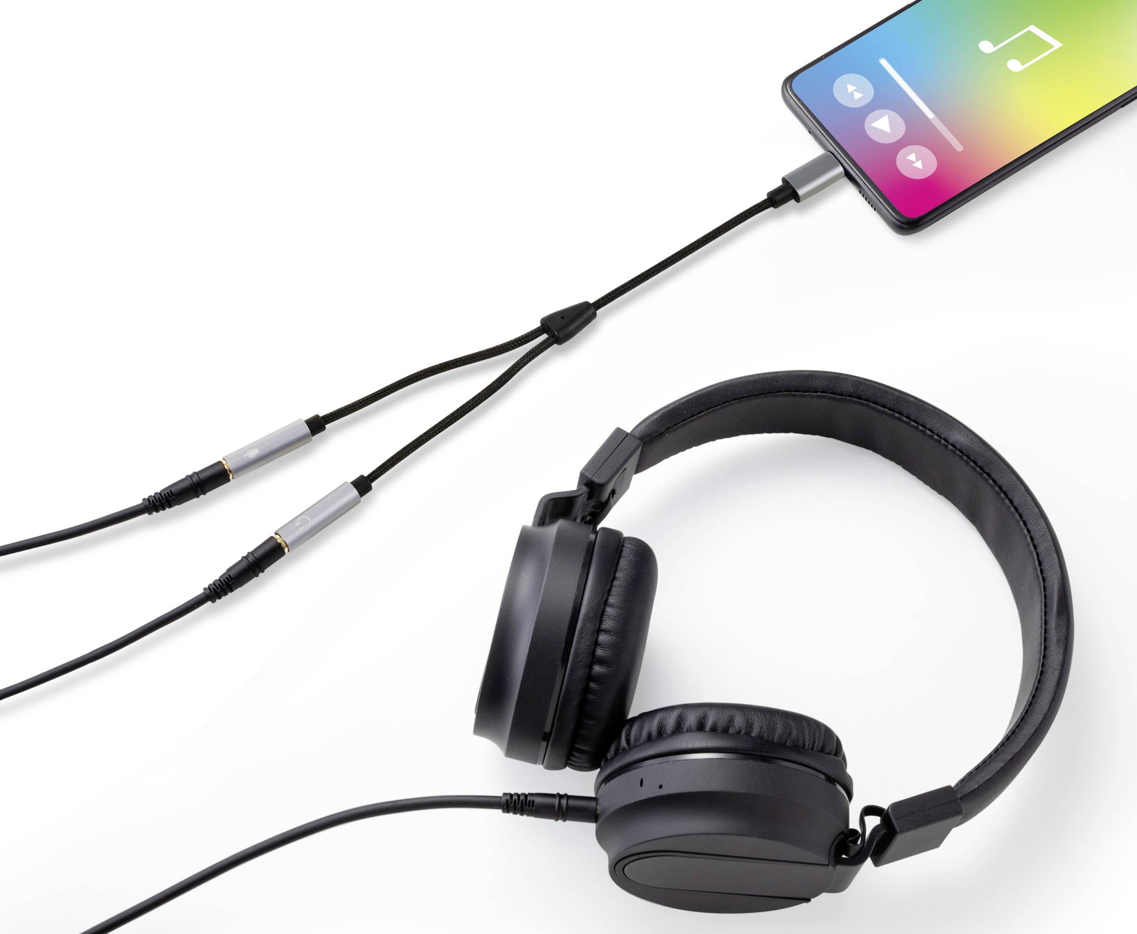 Smartphone s hudební aplikací je připojeno přes rozbočovač dvěma kabely; jeden kabel vede k černým over-ear sluchátkám.