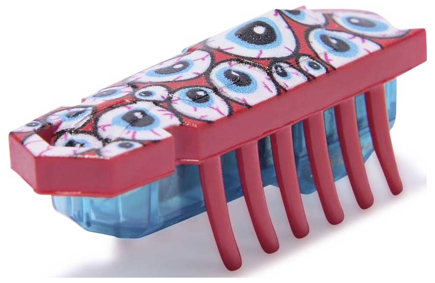 Malá, barevná hračka s červenýma nohama a několika namalovanýma očima na horní straně. Vypadá jako brouk nebo hmyz.