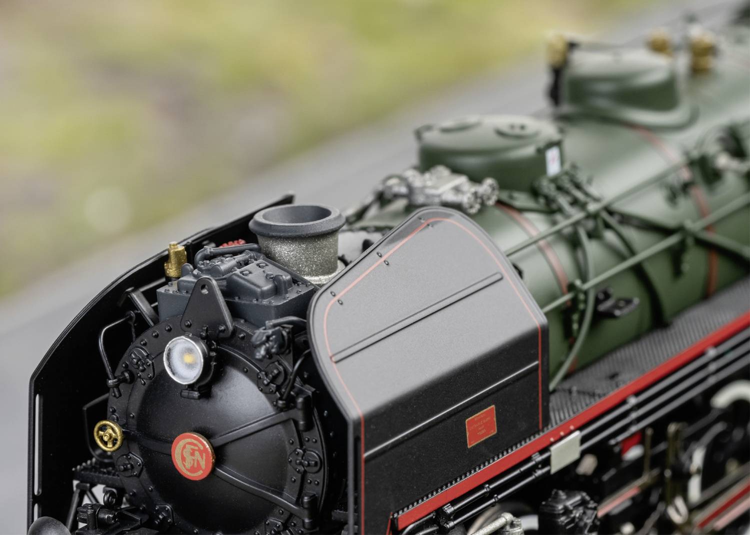 Detailní záběr klasické parní lokomotivy s černým a červeným nátěrem, který odhaluje detaily mechaniky a designu.