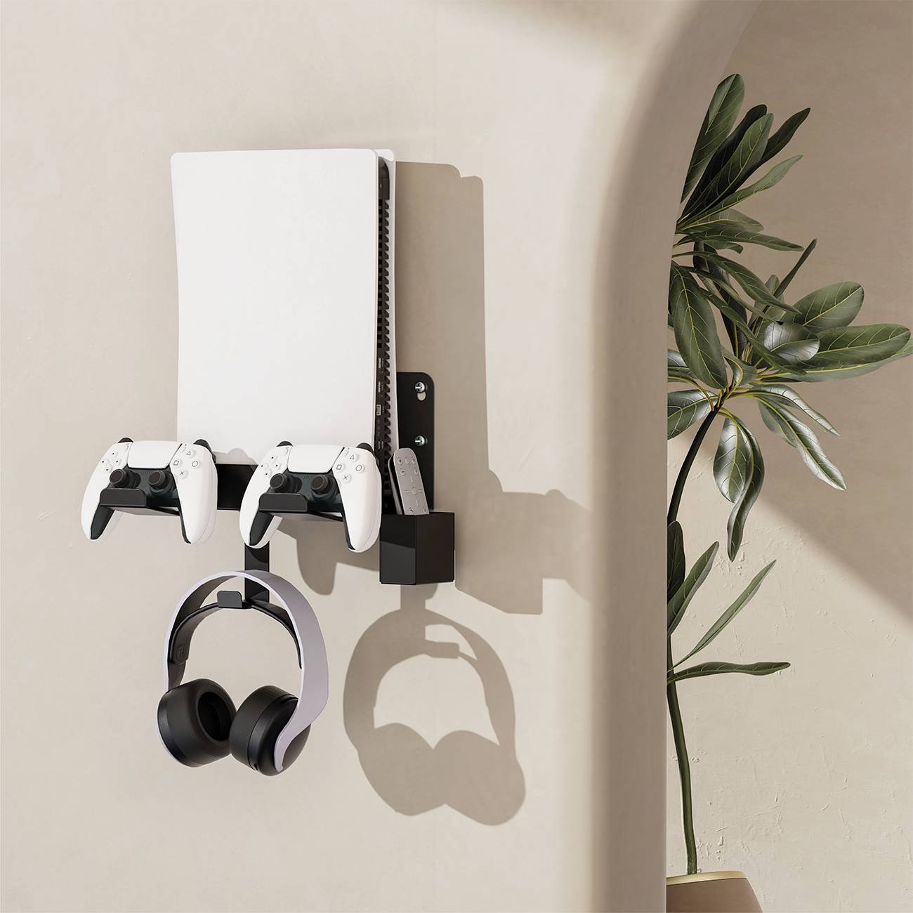 Bílá herní konzole upevněná na nástěnném držáku se dvěma ovladači a černými sluchátky pod ní. Vedle je umístěna zelená rostlina.