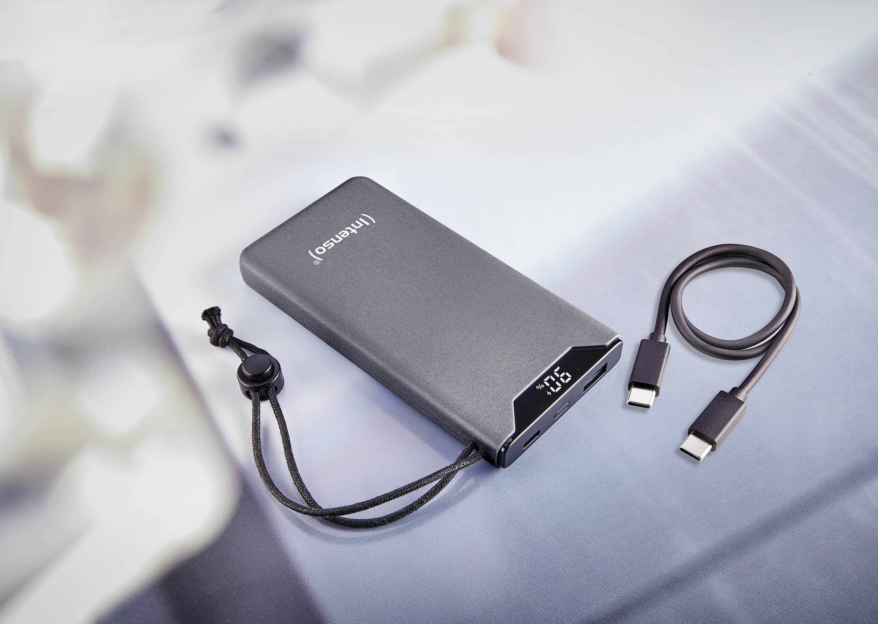 Powerbanka s digitálním displejem, který ukazuje '65', vedle ní USB-C kabel. Vhodná pro nabíjení zařízení na cestách.