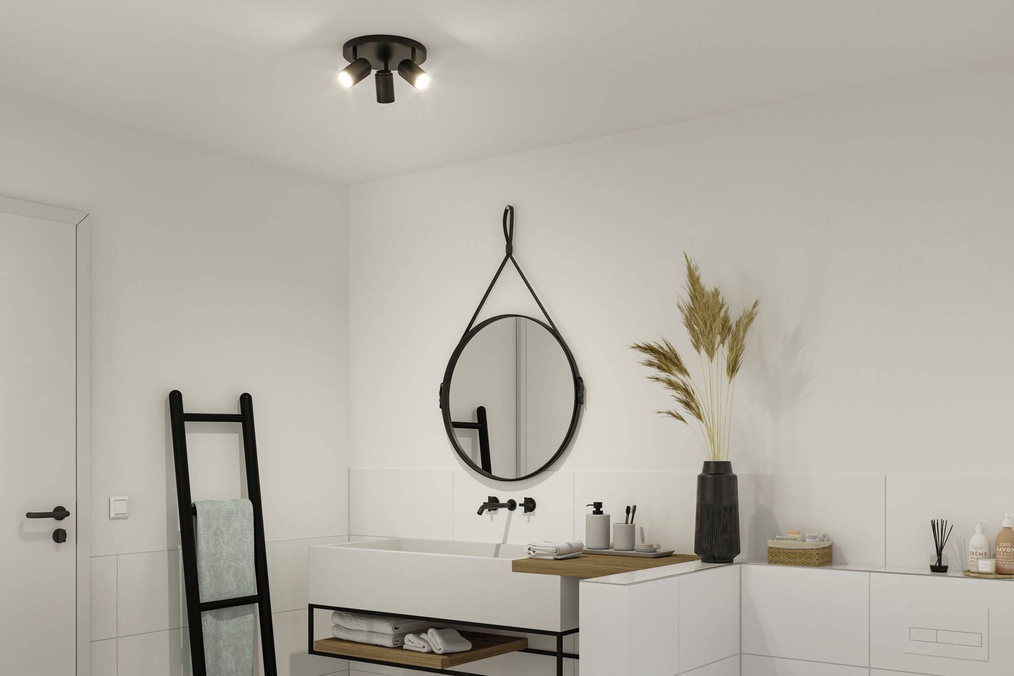 Koupelna s moderním designem, která zobrazuje kulatý zrcadlo na stěně, umyvadlo a dekorace jako jsou žebřík na ručníky a váza.
