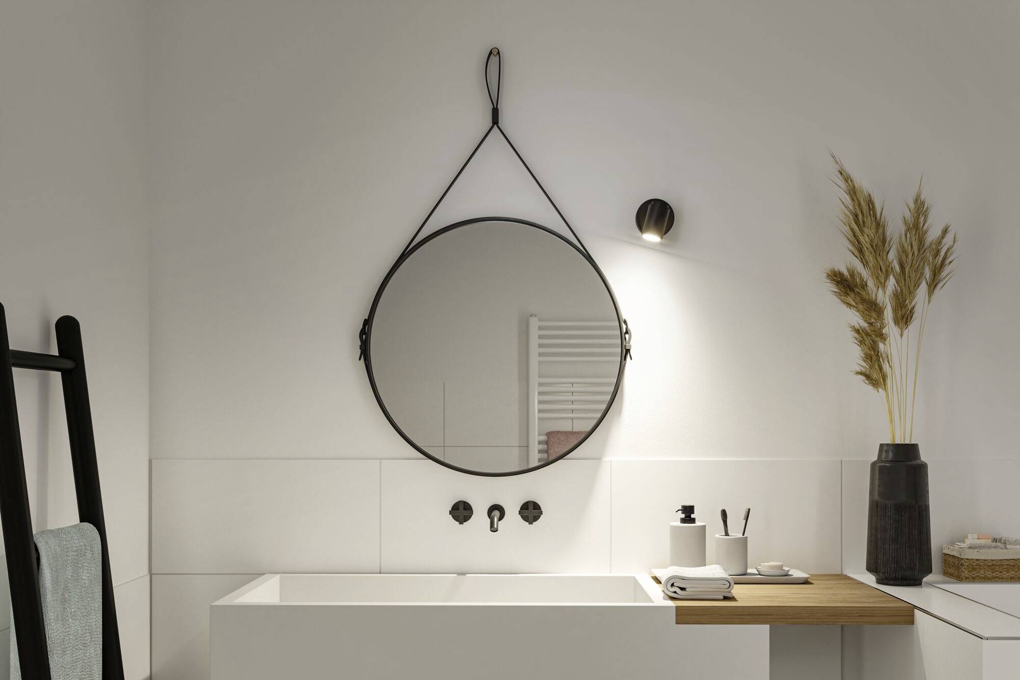 Moderní koupelna s kulatým zrcadlem na stěně, pod ním umyvadlo s baterií a dřevěná police s doplňky.