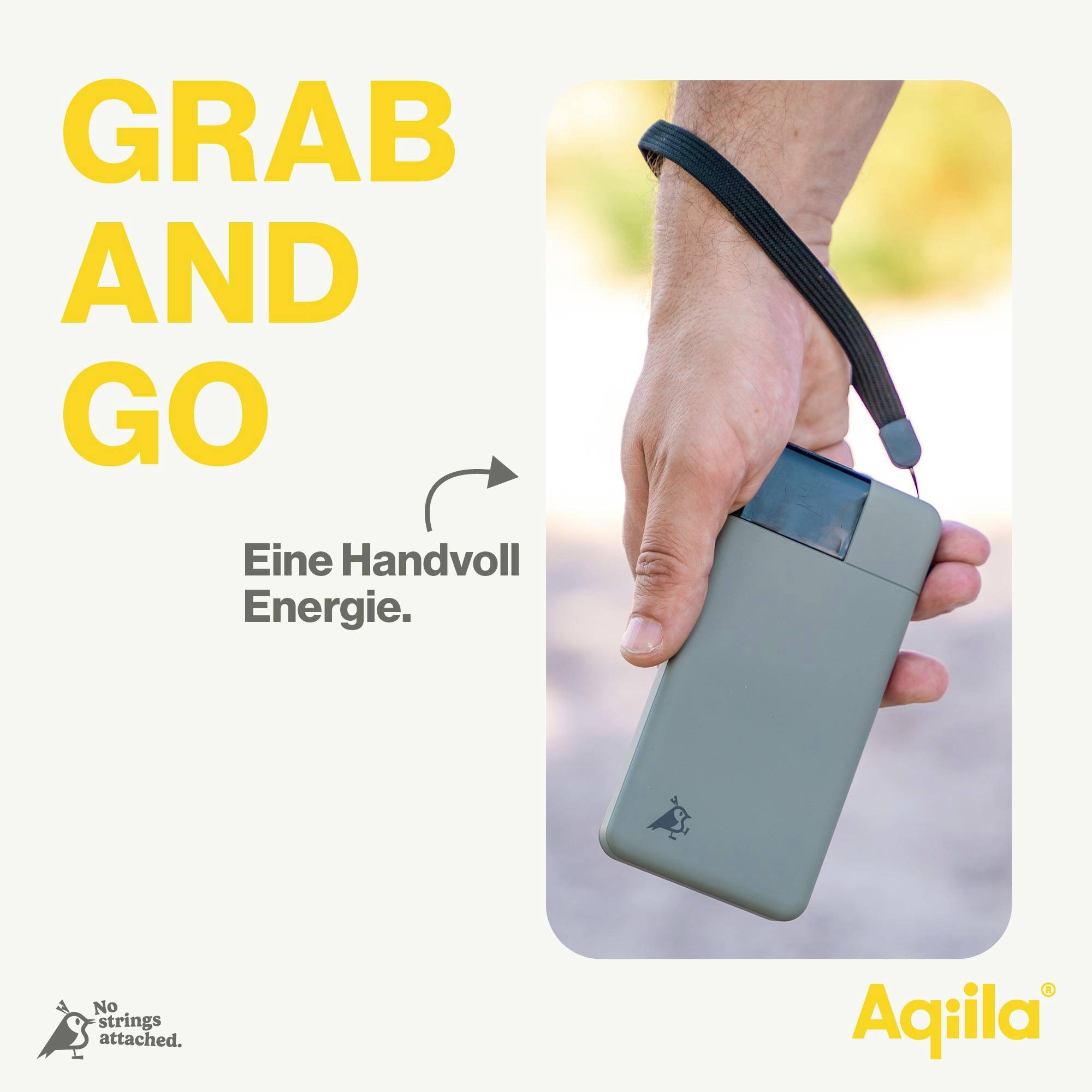 Ruka drží přenosnou powerbabanku s nápisem 'GRAB AND GO'. Text: 'Hrst energie'. Logo značky 'Aqiila'.